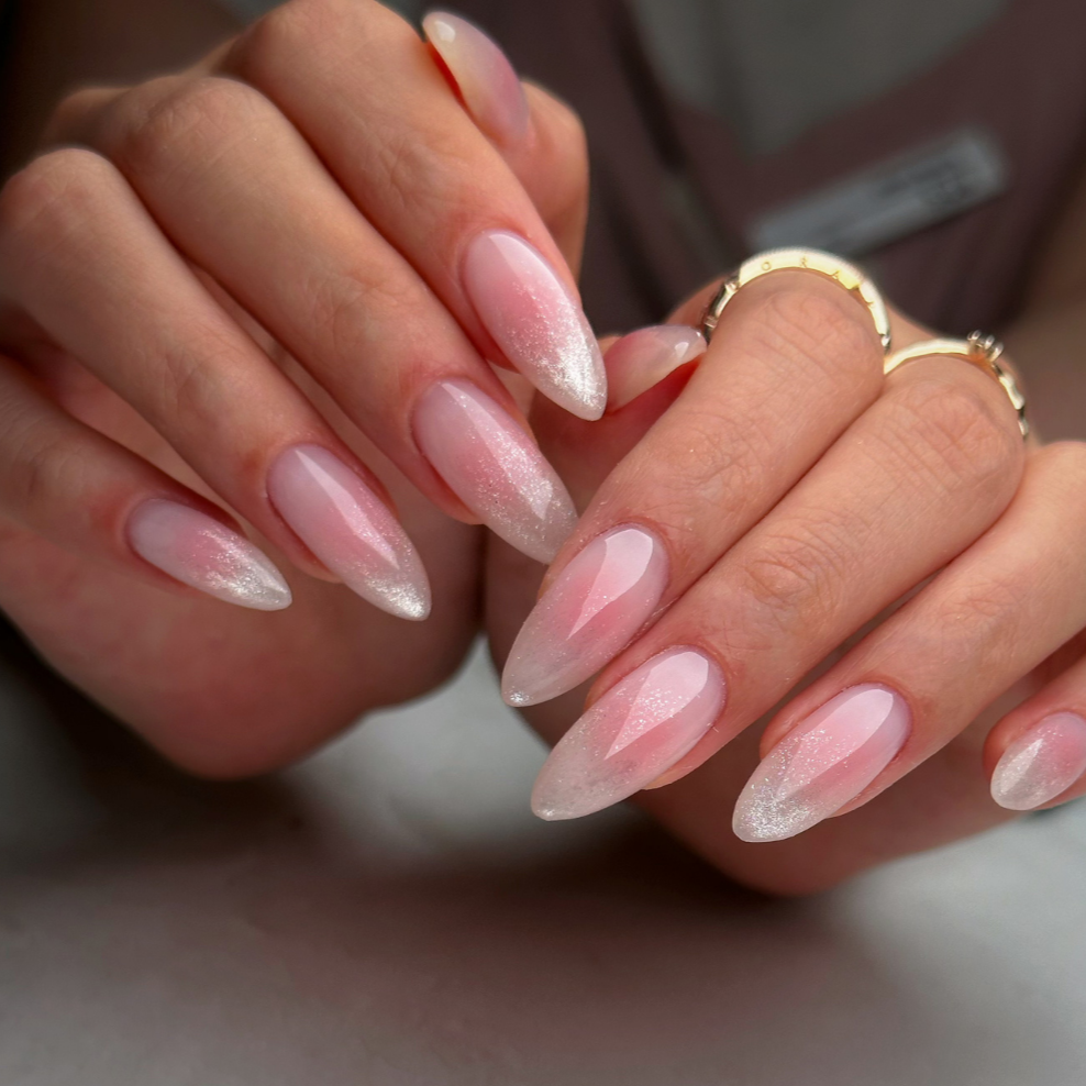 Close-up of well-manicured nails painted with light pink nail polish, held partly closed with fingers gently bent.