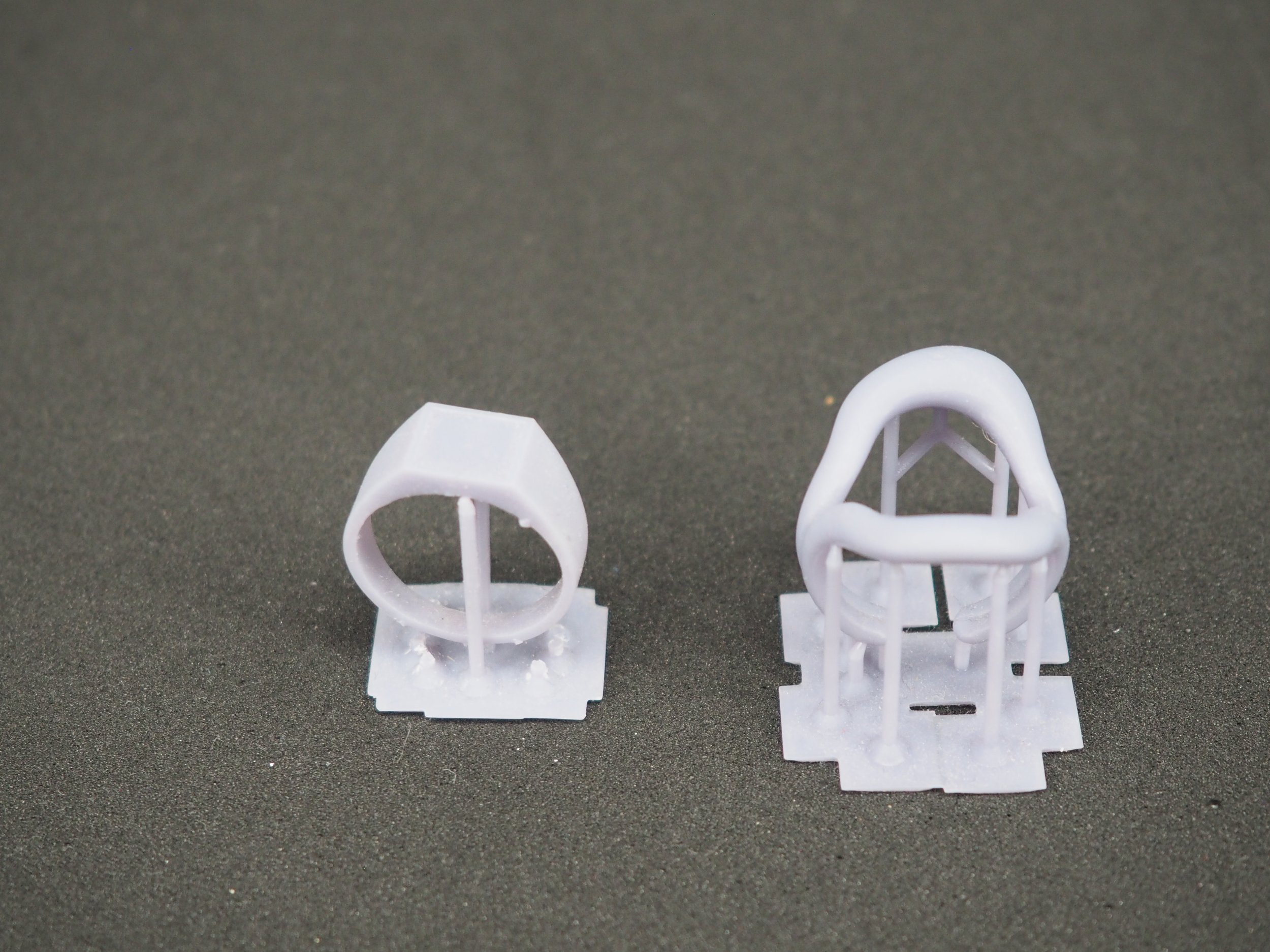 Dos modelos de anillos impresos en 3D sobre una superficie oscura.
