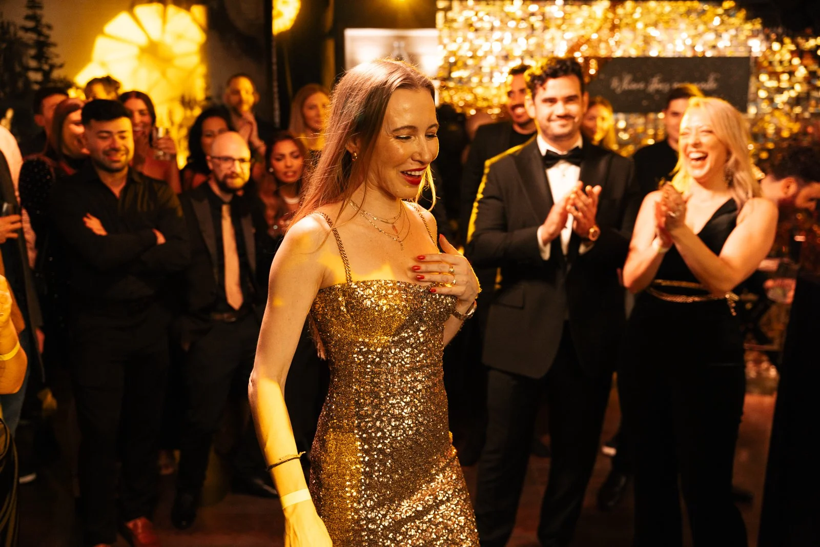 Guests applauding a woman in a gold dress at an awards night