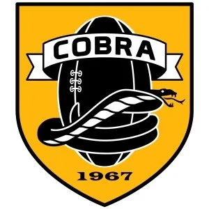 A shield-shaped logo with a yellow background, featuring a black football ball, a snake coiled around it, a small snake with a forked tongue, and a banner with the word 'COBRA'. The year 1967 is at the bottom.