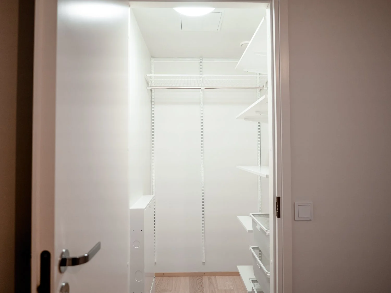 Empty walk-in closet with white shelves and hanging rod