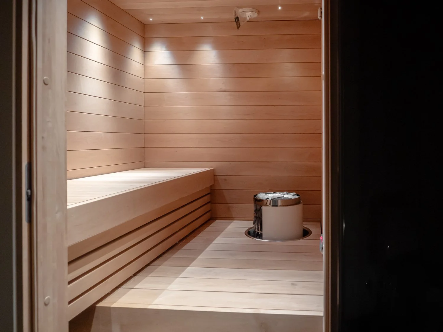 Interior of a wooden sauna with benches and a heater.