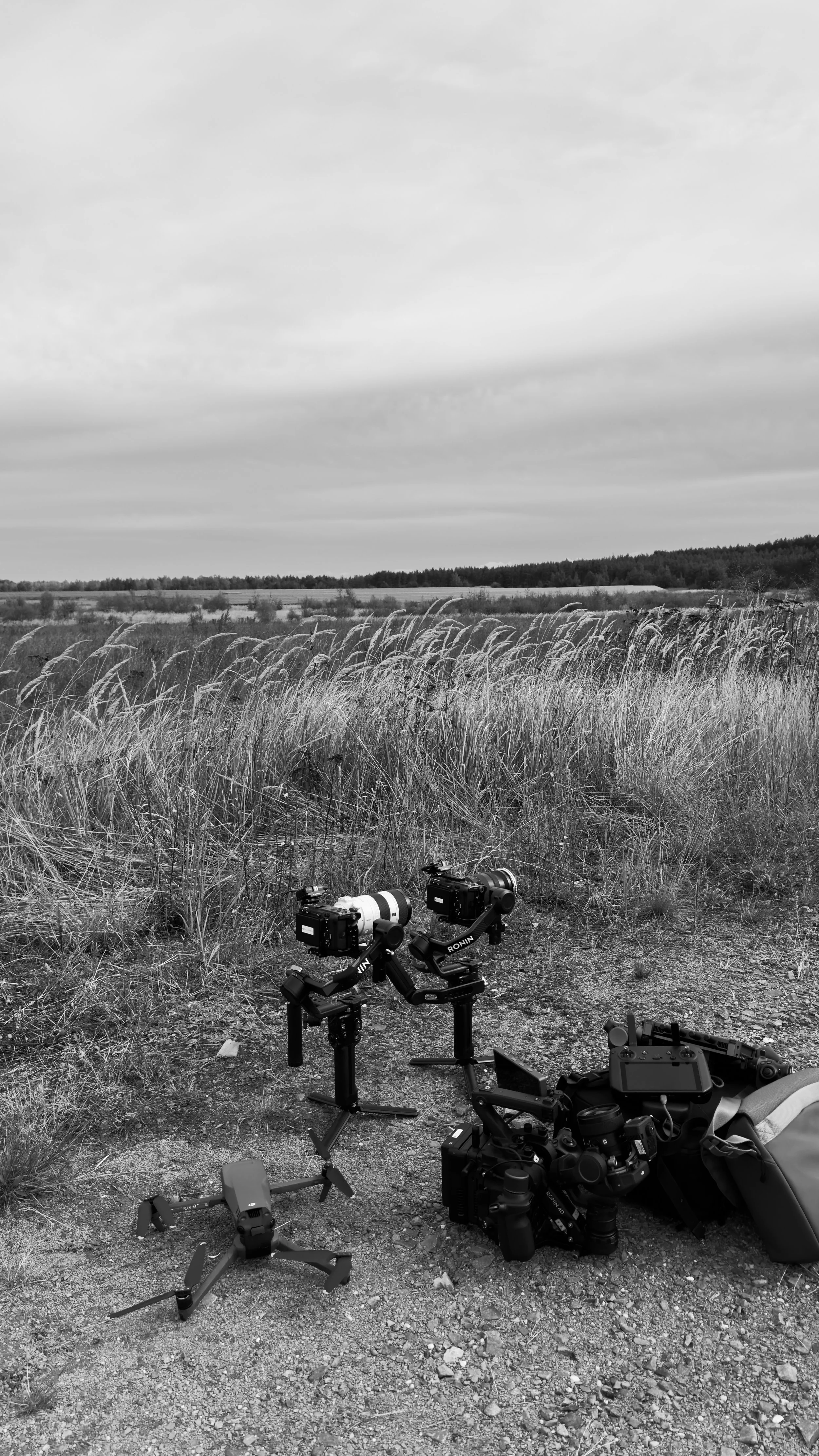 Professional camera equipment and drones on grassy landscape