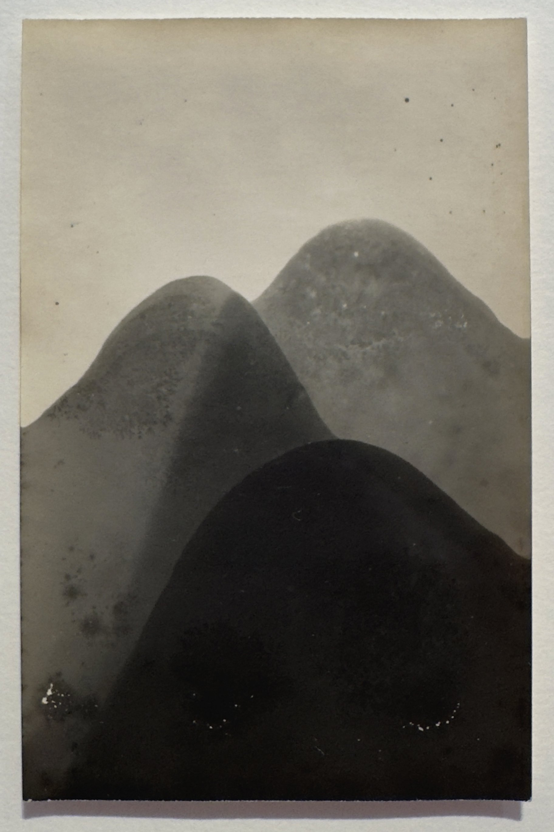 Black and white photograph of three mountain peaks with mist or fog around them.