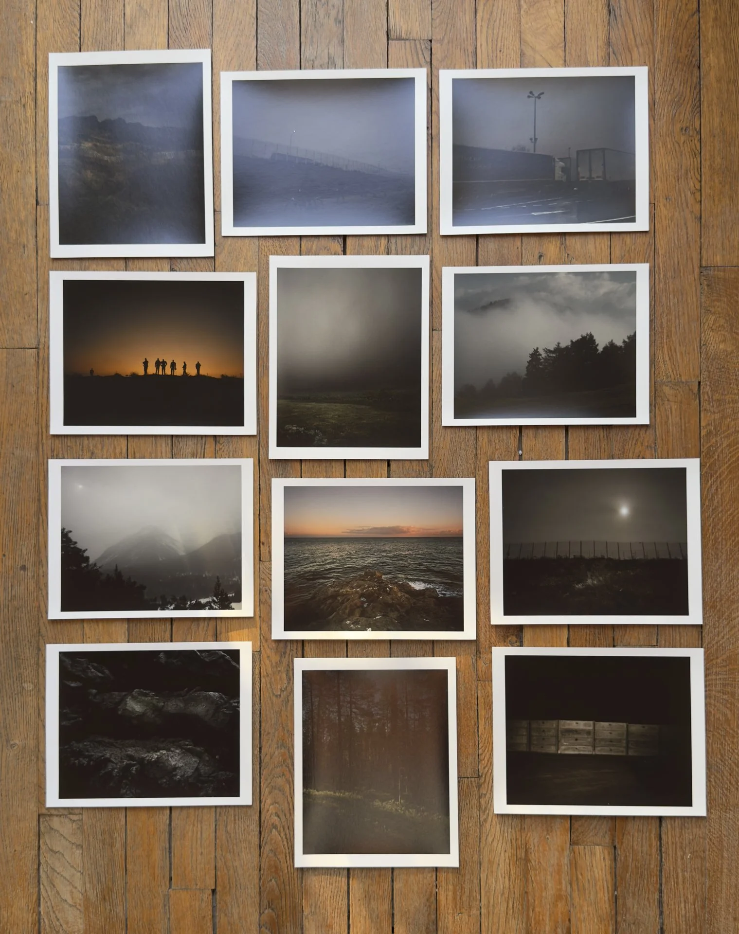 A portfolio of nine landscape photographs arranged on a wooden surface. The portfolio is neat and well assembled.
