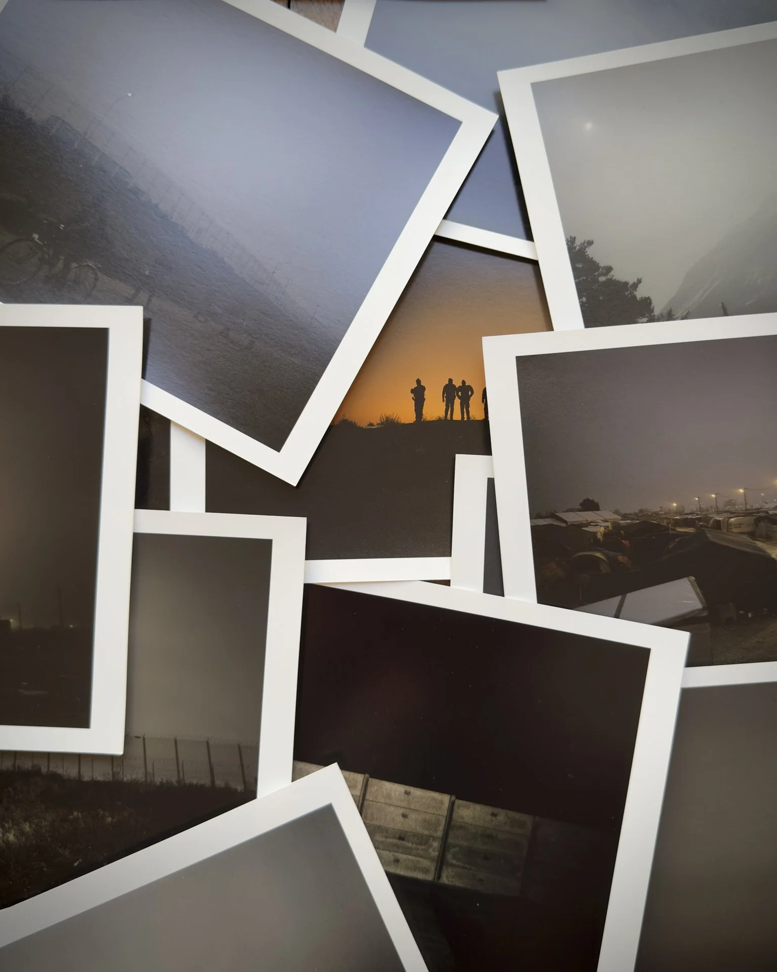 Multiple printed photographs scattered on a surface. A messy portfolio of photographic prints.