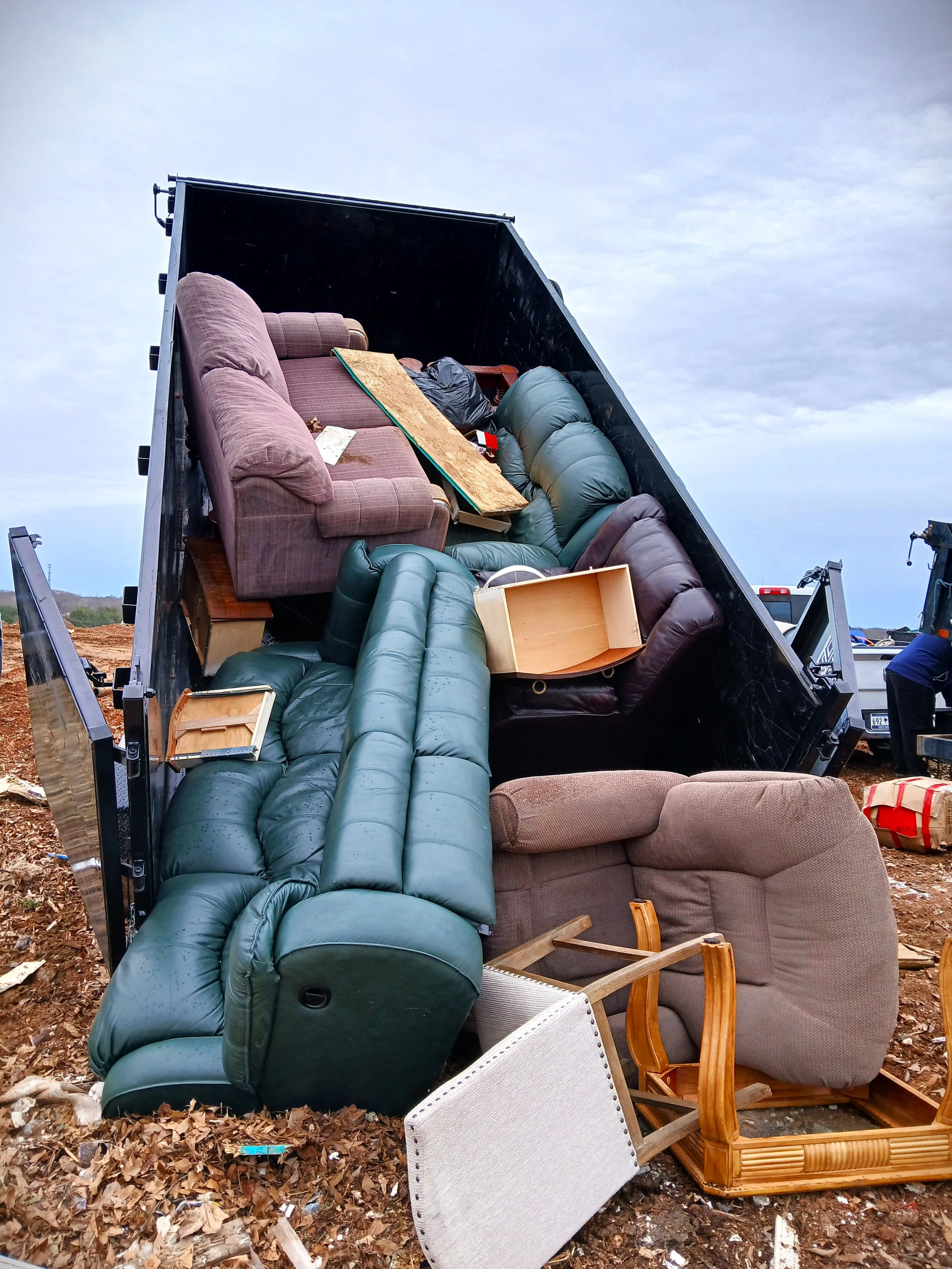 Dump truck loaded with couches and old household items.