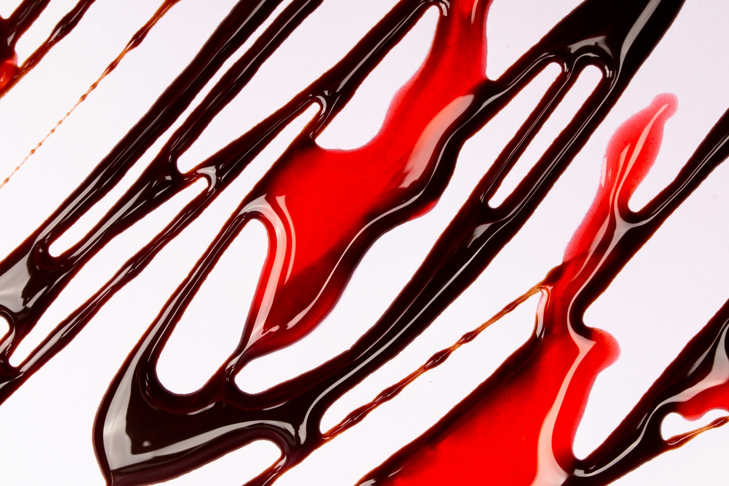 Schwarz- und Rotwein, der auf einer weißen Oberfläche verschmiert ist, mit diagonalen Strichen.