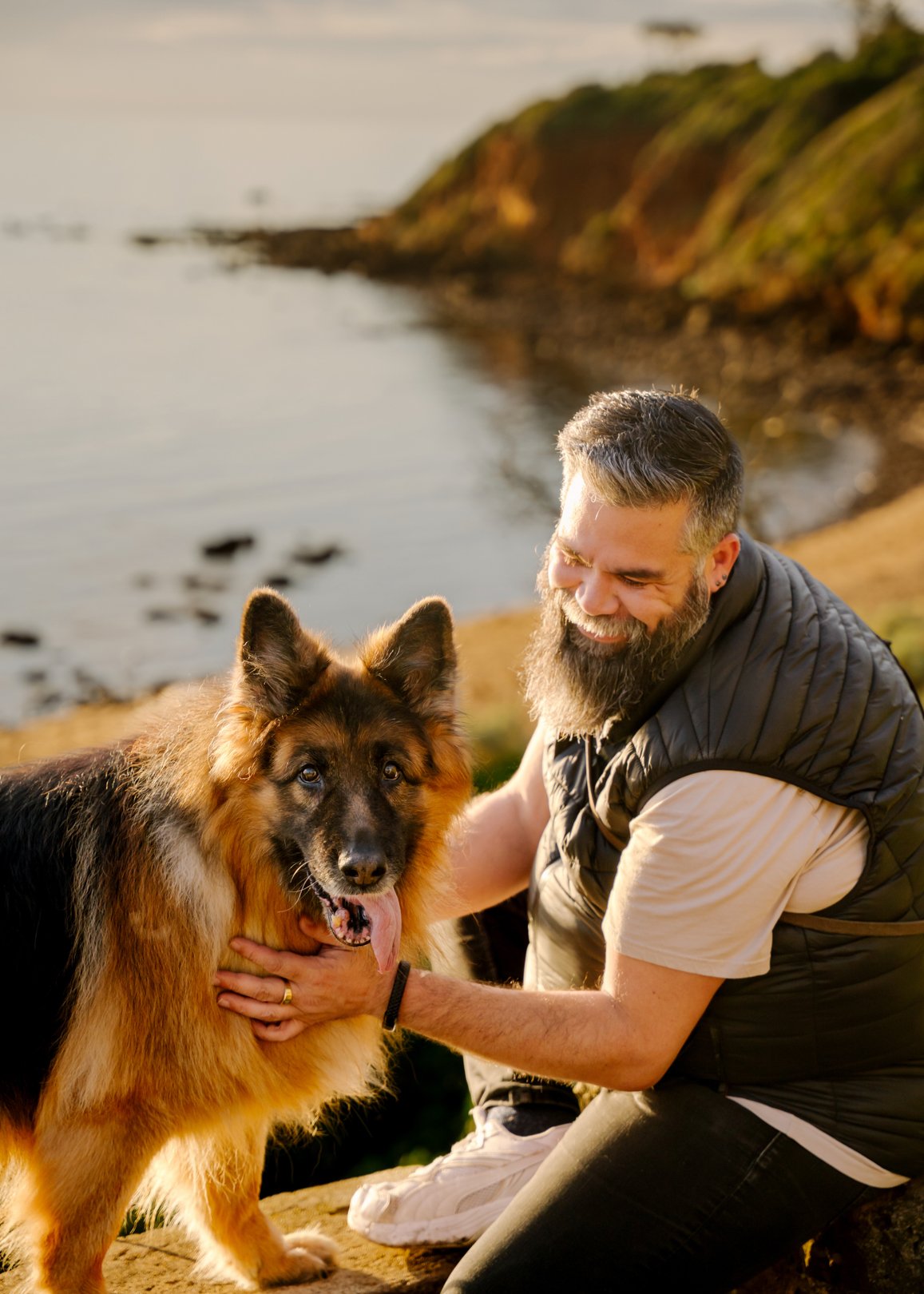 Dan crouched beside his German Shepherd Dexter on the clifftop at Royal Beach, Mornington