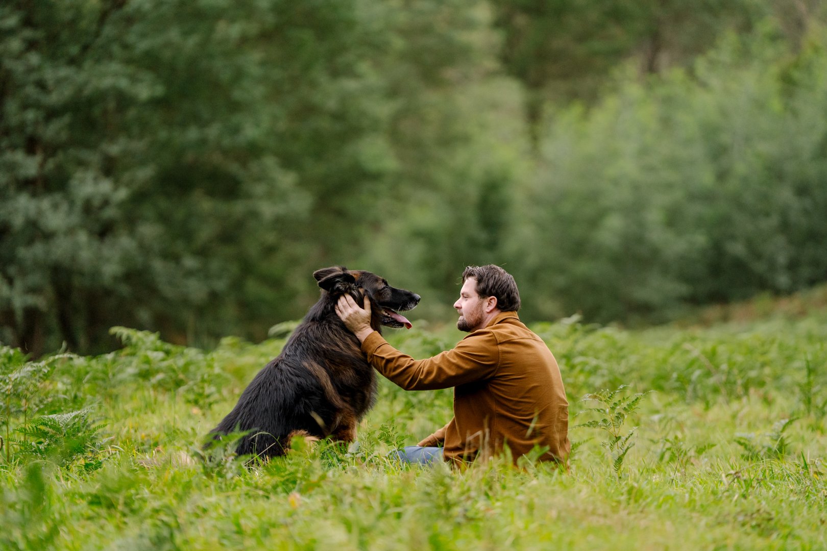 Joel sitting among the ferns with Archie during their Dandenong Ranges dog photoshoot