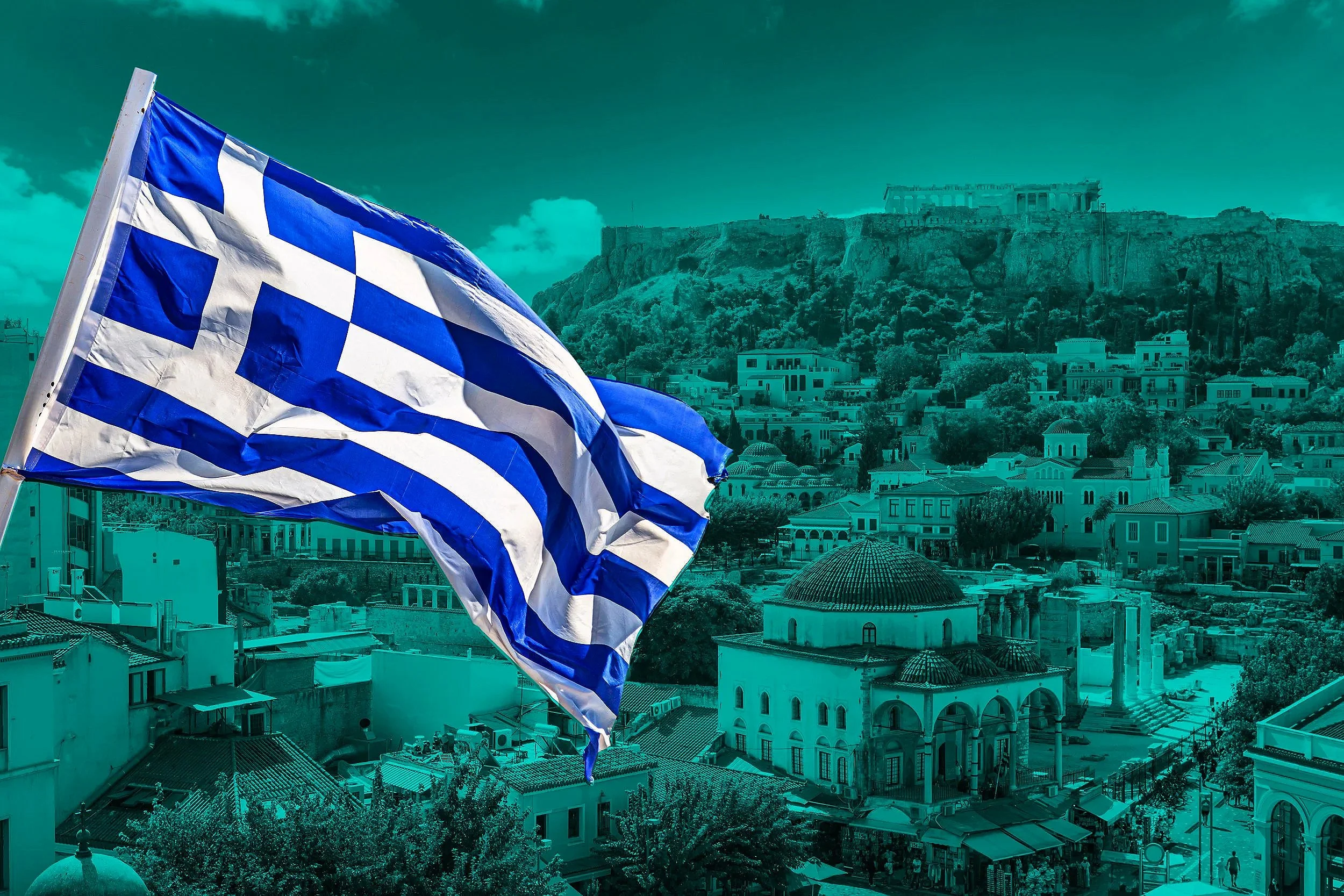 En grekisk flagga svajar framför en stad med gamla byggnader och Akropolisonen på berget i bakgrunden.
