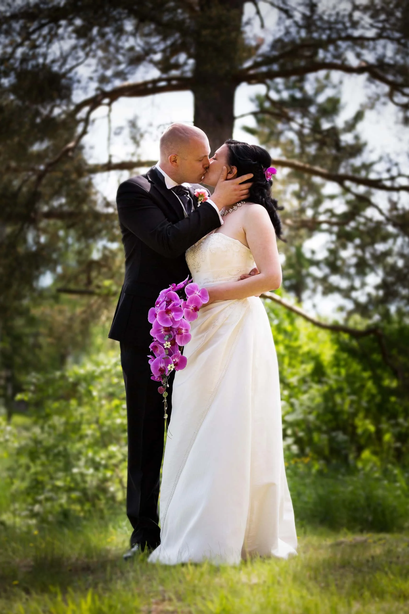 Hääpari suutelee toisiaan ulkona, taustalla metsä.