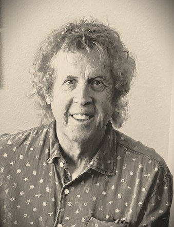Black and white photo of an elderly woman with curly hair wearing a polka dot shirt.