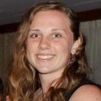 A young woman with long wavy brown hair smiling at the camera.