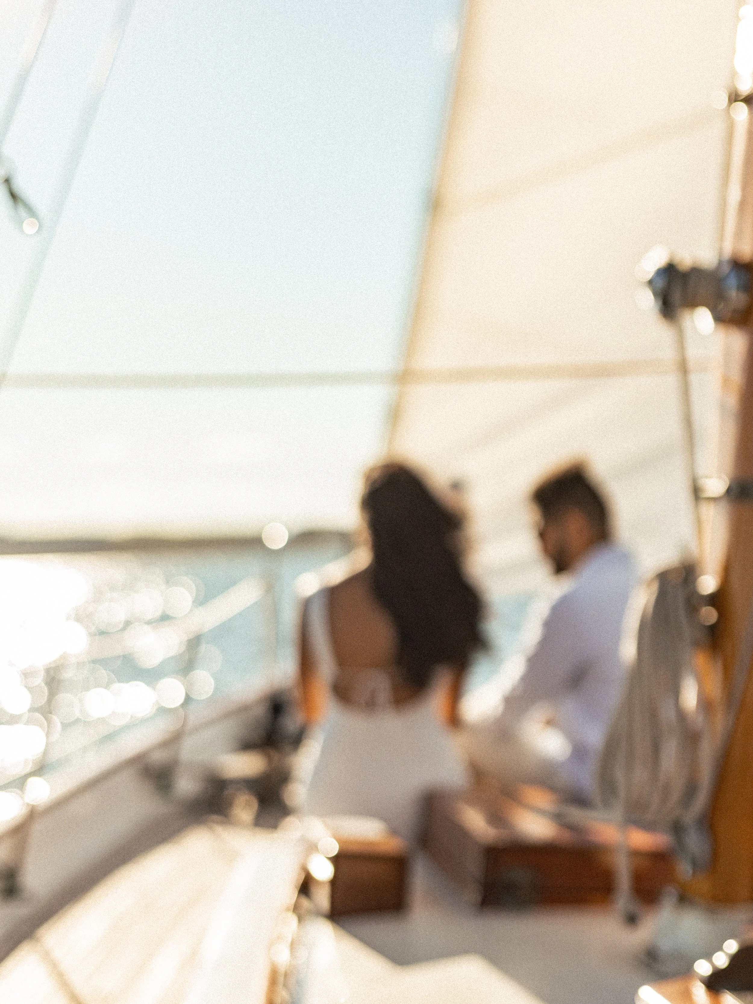 Two people sitting on a boat looking out at the water, with the sun shining brightly.