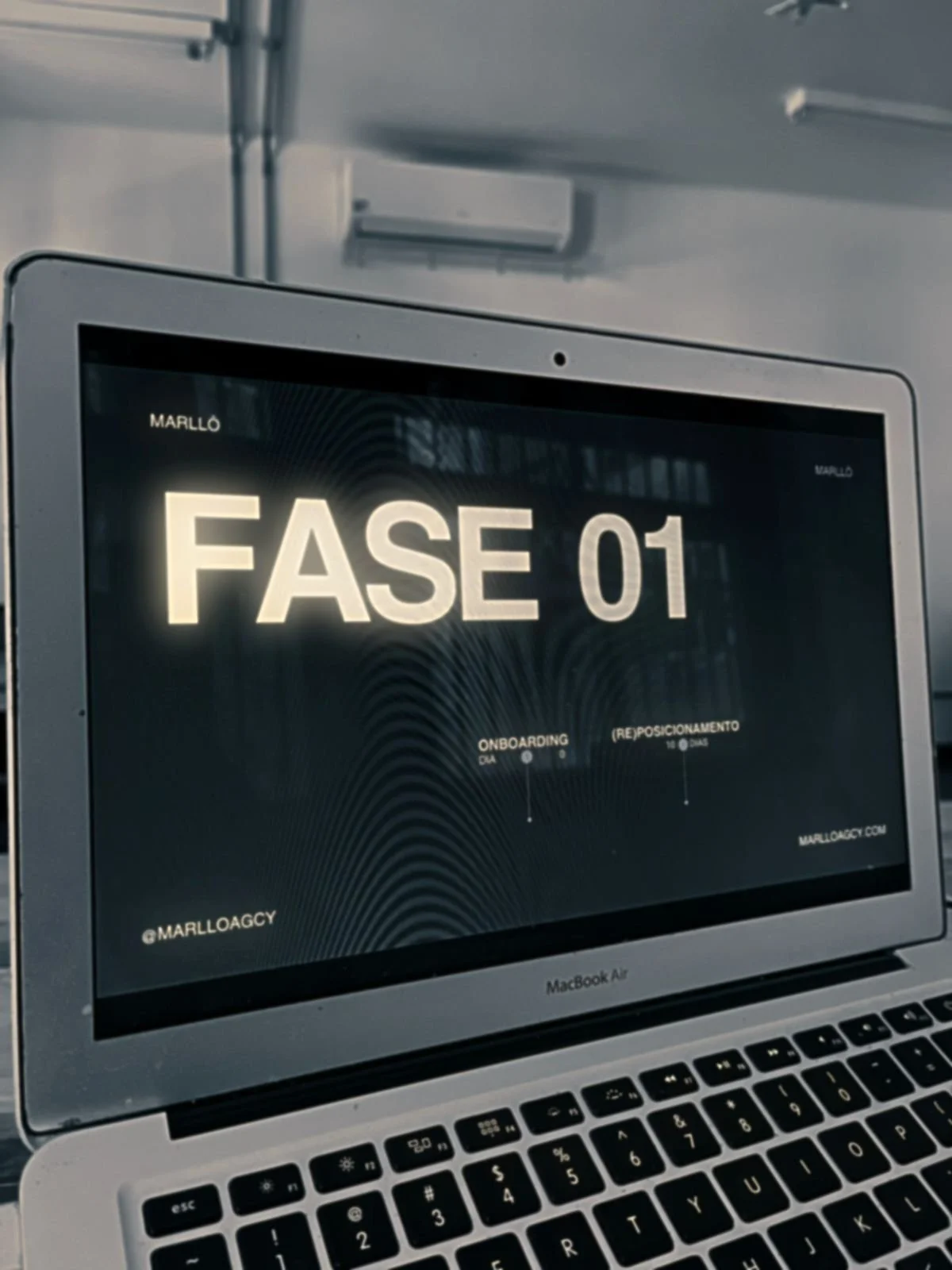 A laptop screen displaying a digital sign that reads 'FASE 01' with smaller text indicating boarding information and a website URL, in a setting that appears to be an airport or transportation hub.