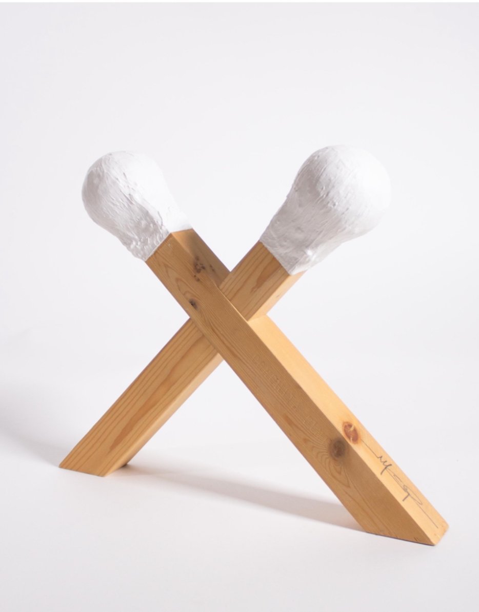 Sculpture of two oversized wooden matchsticks crossed together