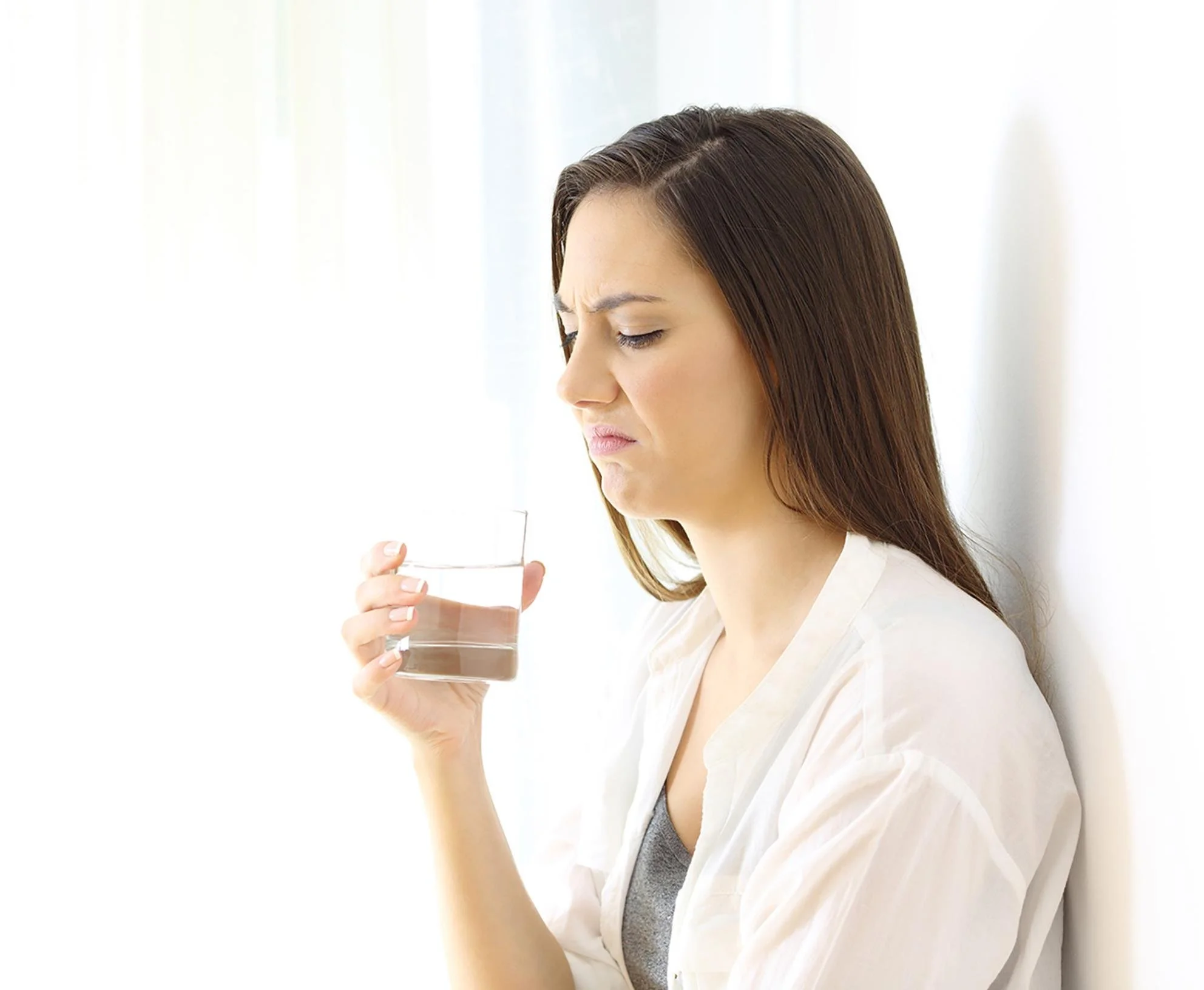 A girl smelling a glass of stinky water