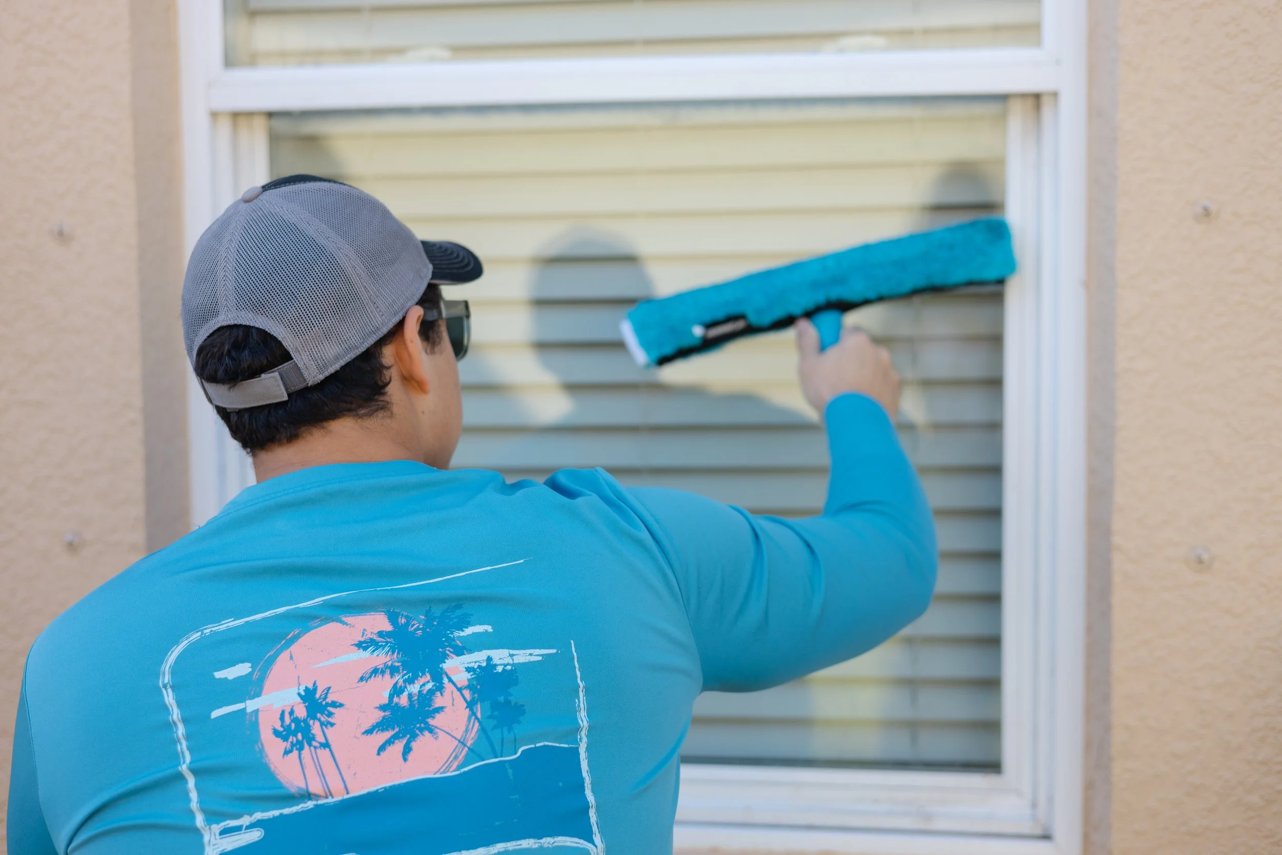 Person cleaning a window with a blue squeegee.