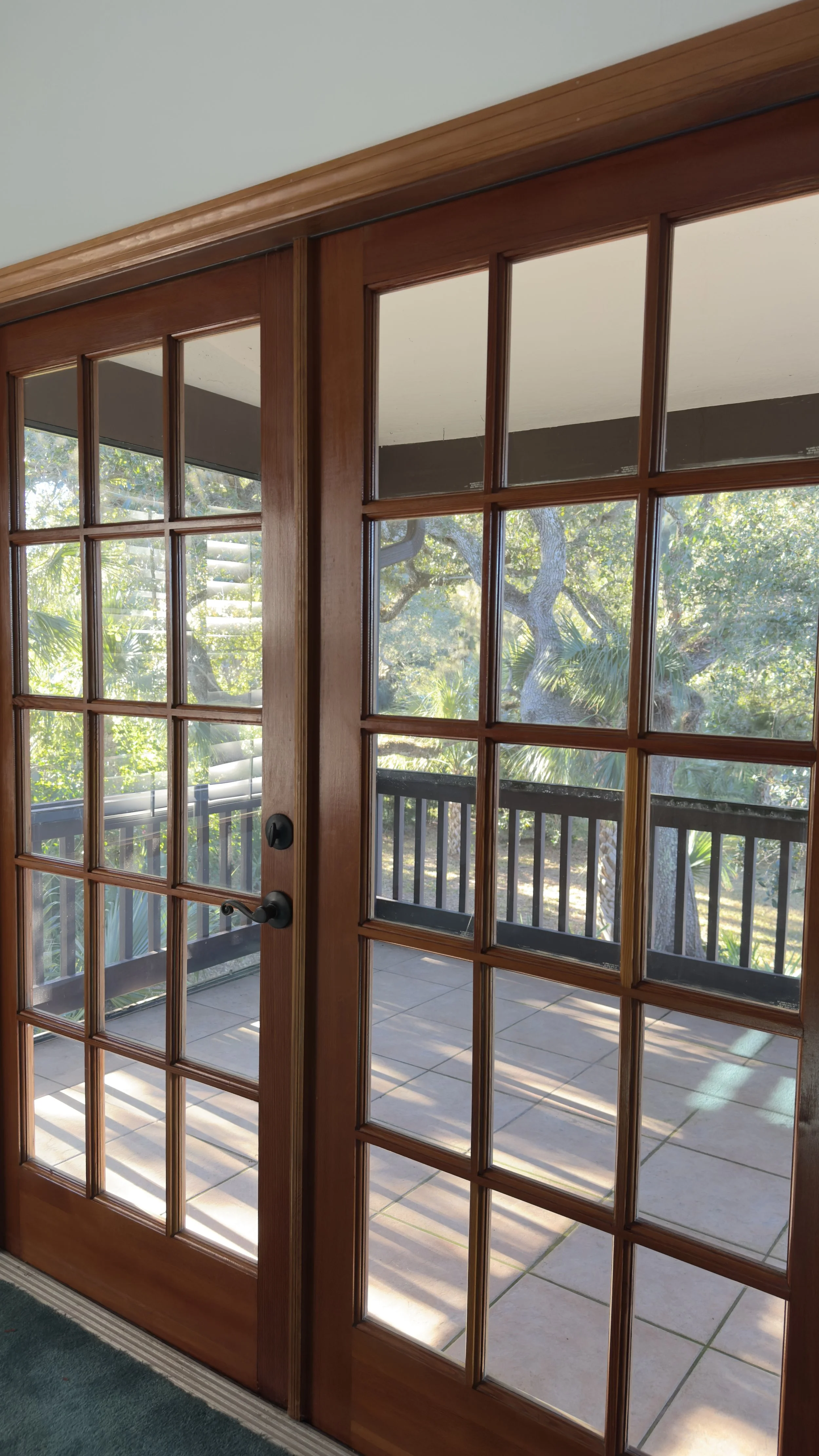 Wood-framed glass doors leading to a screened porch with greenery outside.