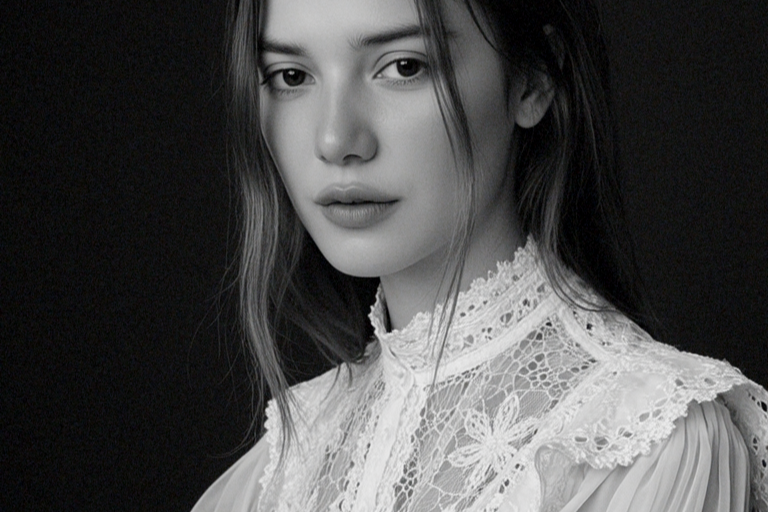 Retrato en blanco y negro de una joven mujer con cabello suelto, vestida con blusa de encaje y cuello alto.