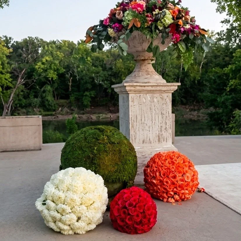 A study in texture and scale! ✨ For this outdoor installation, we paired a classical, weathered urn with minimalist floral spheres for a unexpected modern juxtaposition.

The contrast between the soft white carnations, the vibrant red and orange rose