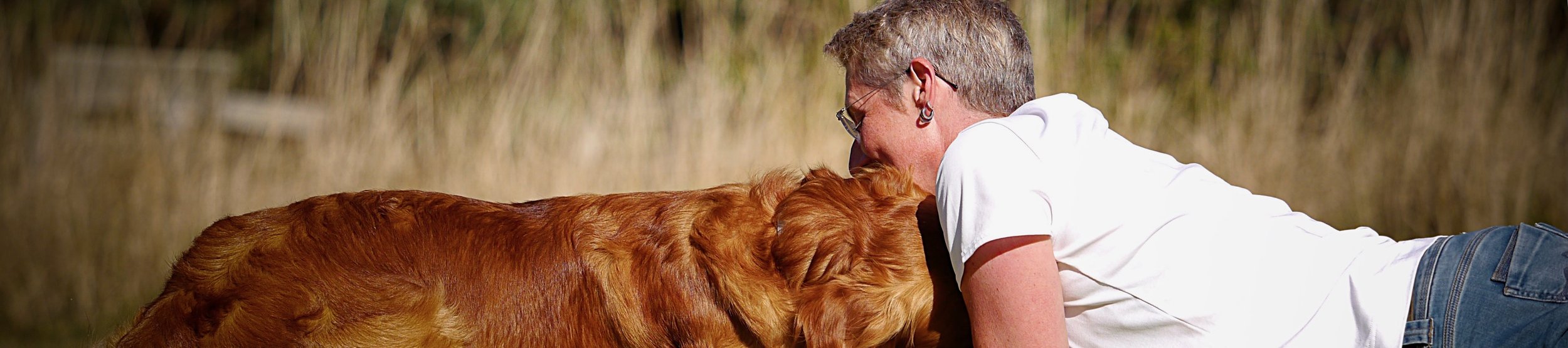 Frau liegt nah bei einem Golden Retriever – warmes, ruhiges Porträt