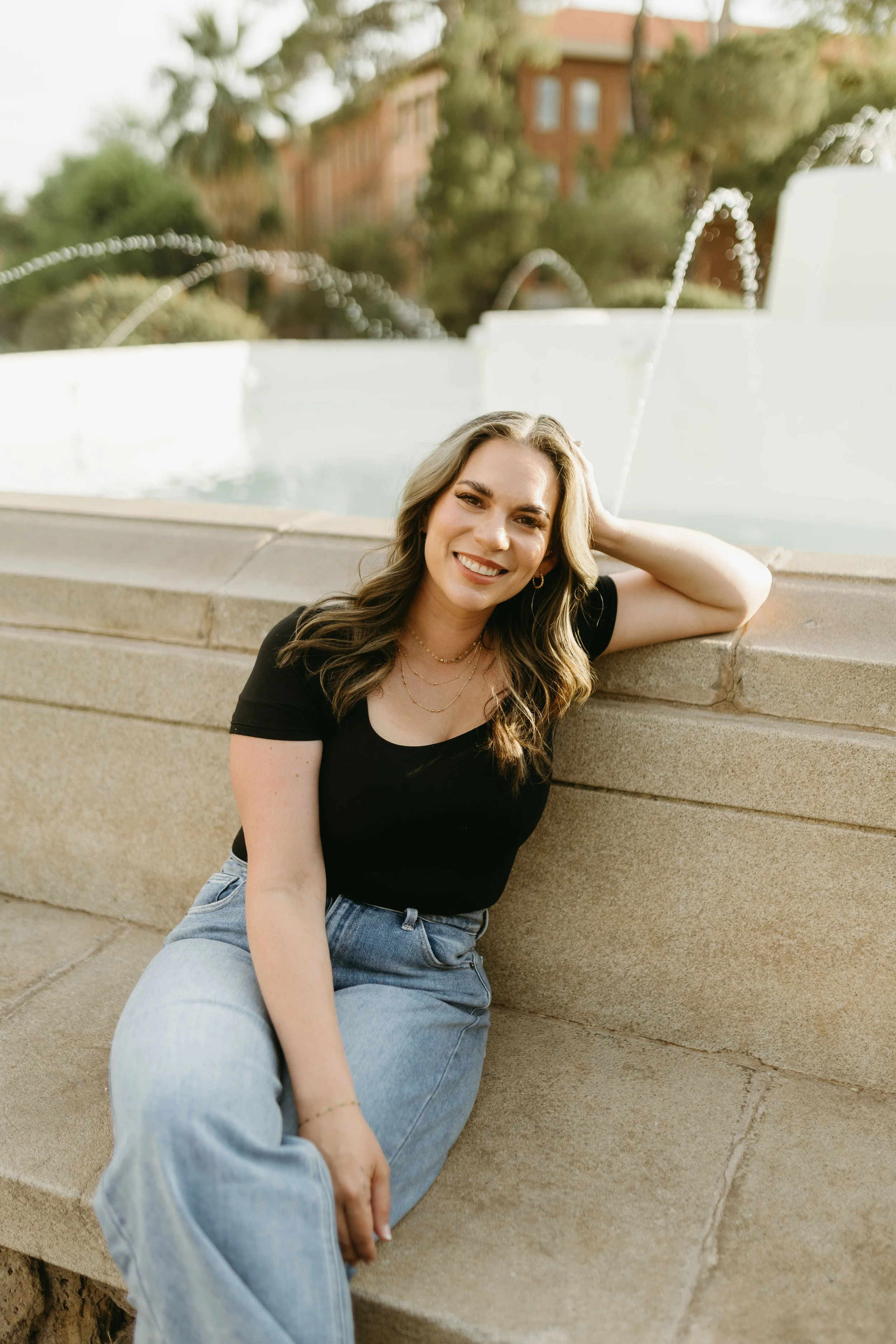 female therapist smiling seated in front of fountain