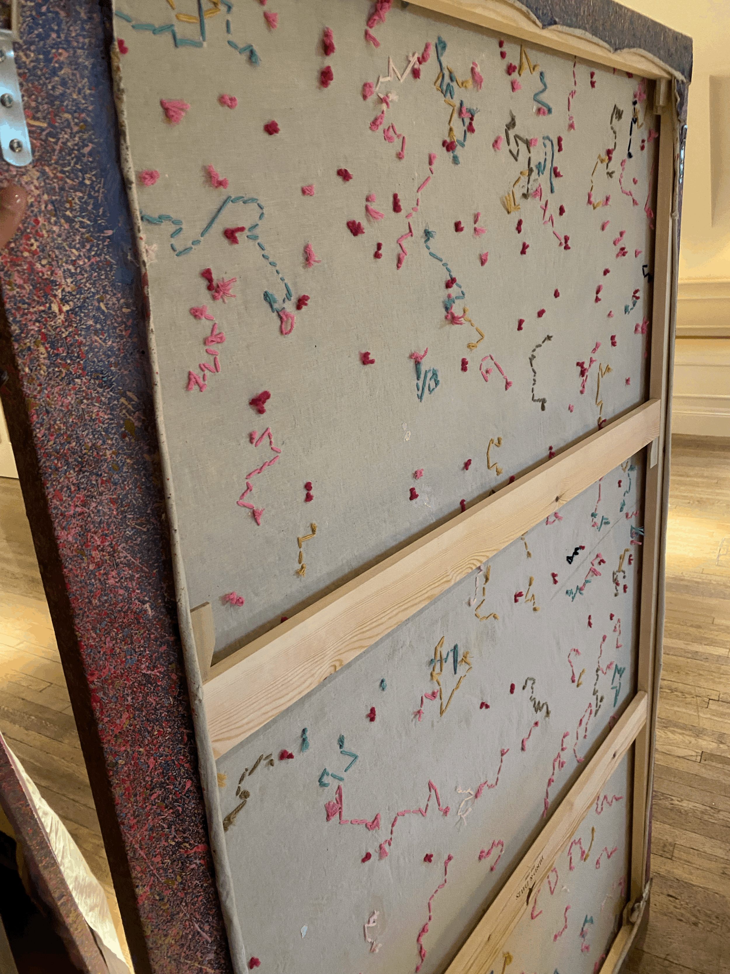 Deconstructed view of Kira Somerset's painting, highlighting stitched threads, unstretched canvas, and exposed wooden stretcher bars.