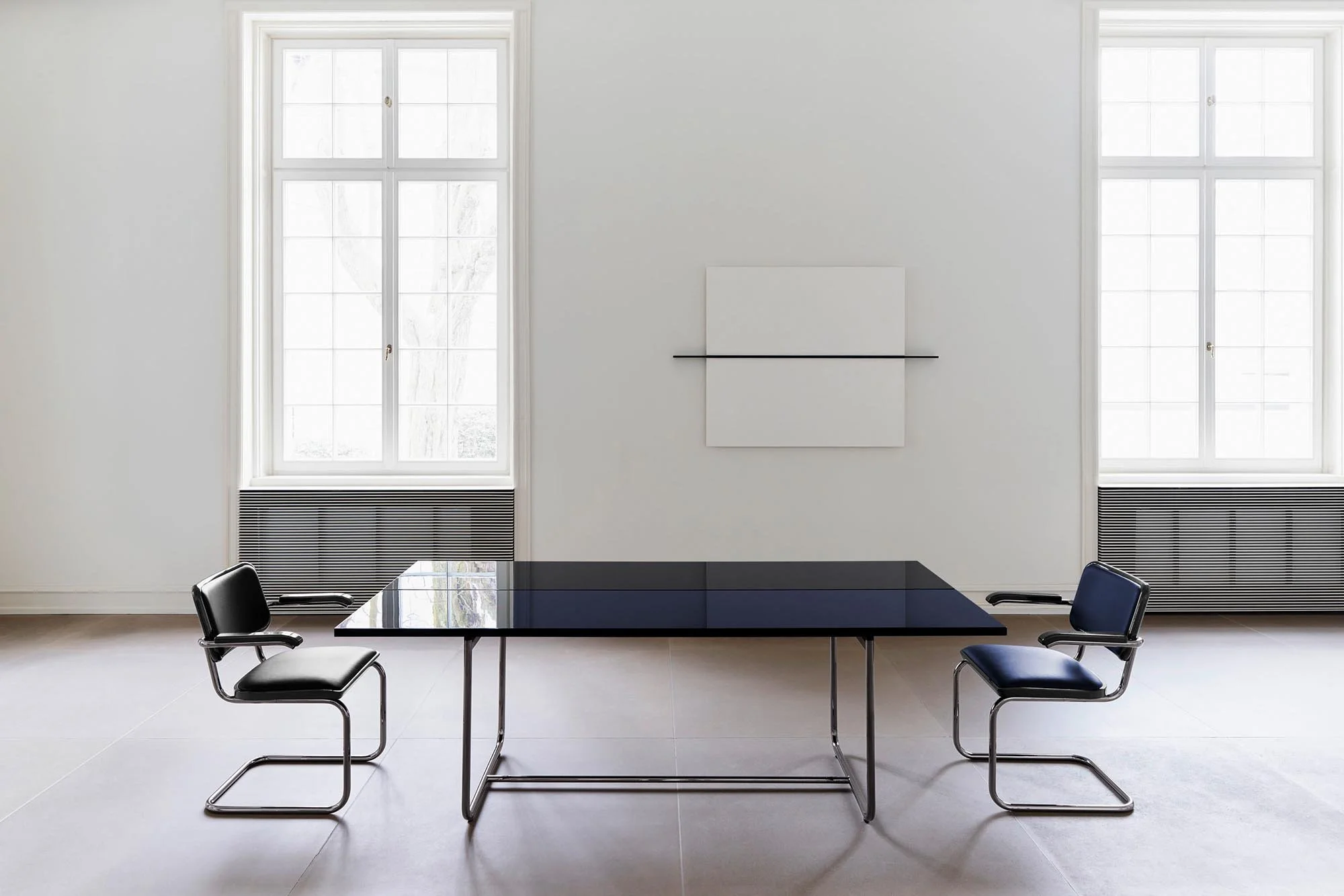 Dark high-gloss JS . THONET S 1070 table with tubular-steel chairs in a restrained interior.