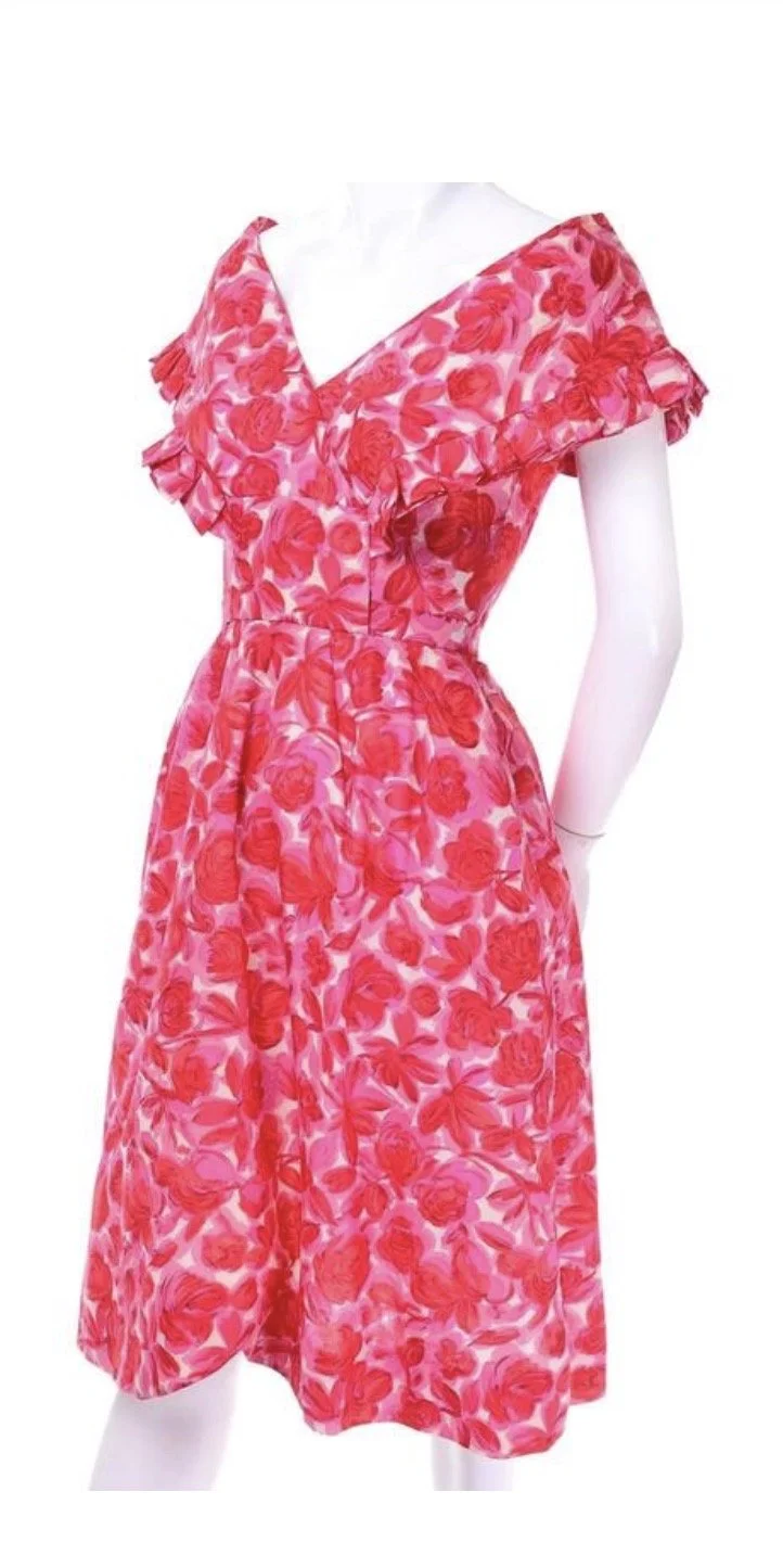 Pink floral vintage dress with ruffled sleeves on a white mannequin.