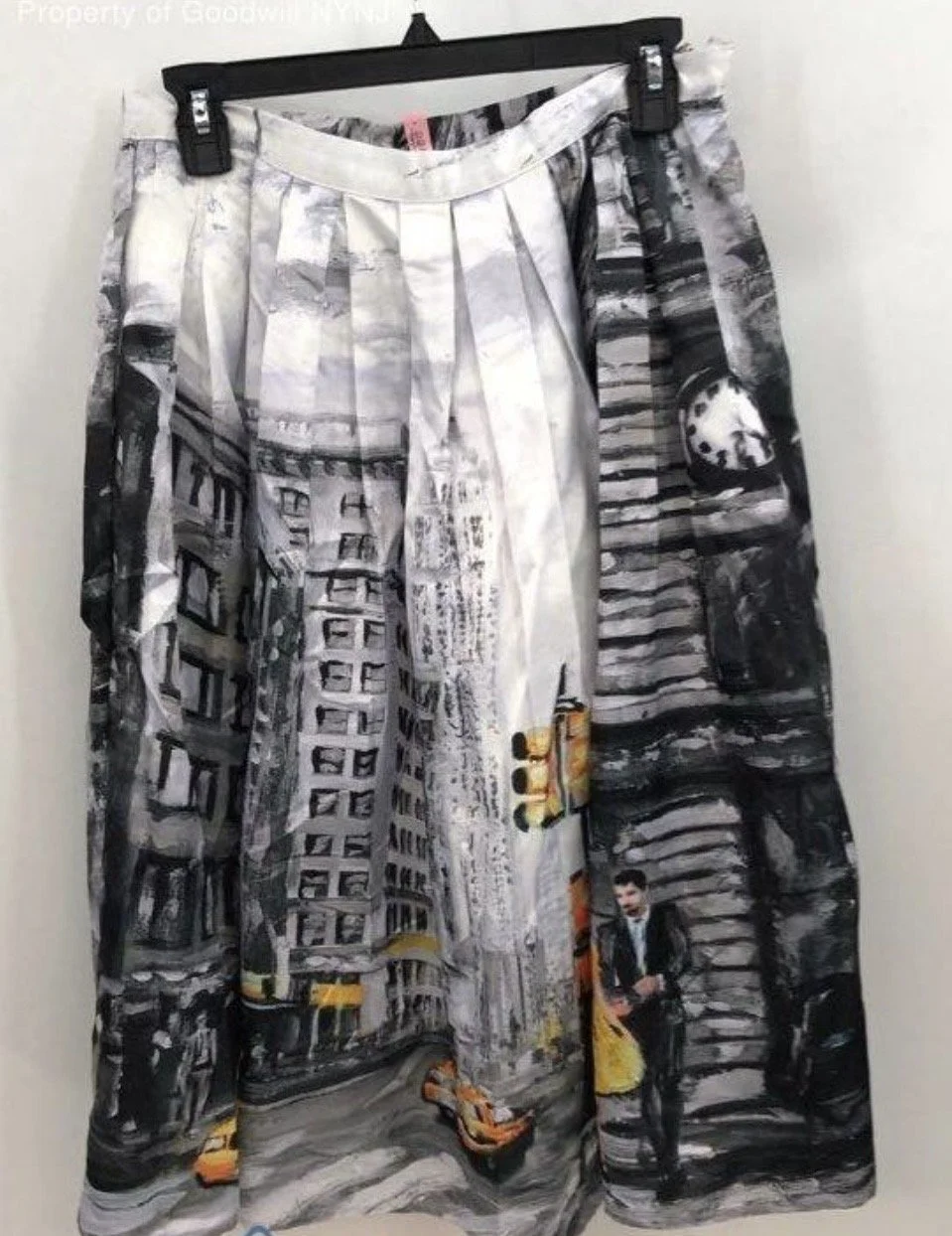 Printed skirt featuring a cityscape with buildings, a man in a suit holding a briefcase, a yellow taxi, and a traffic light.