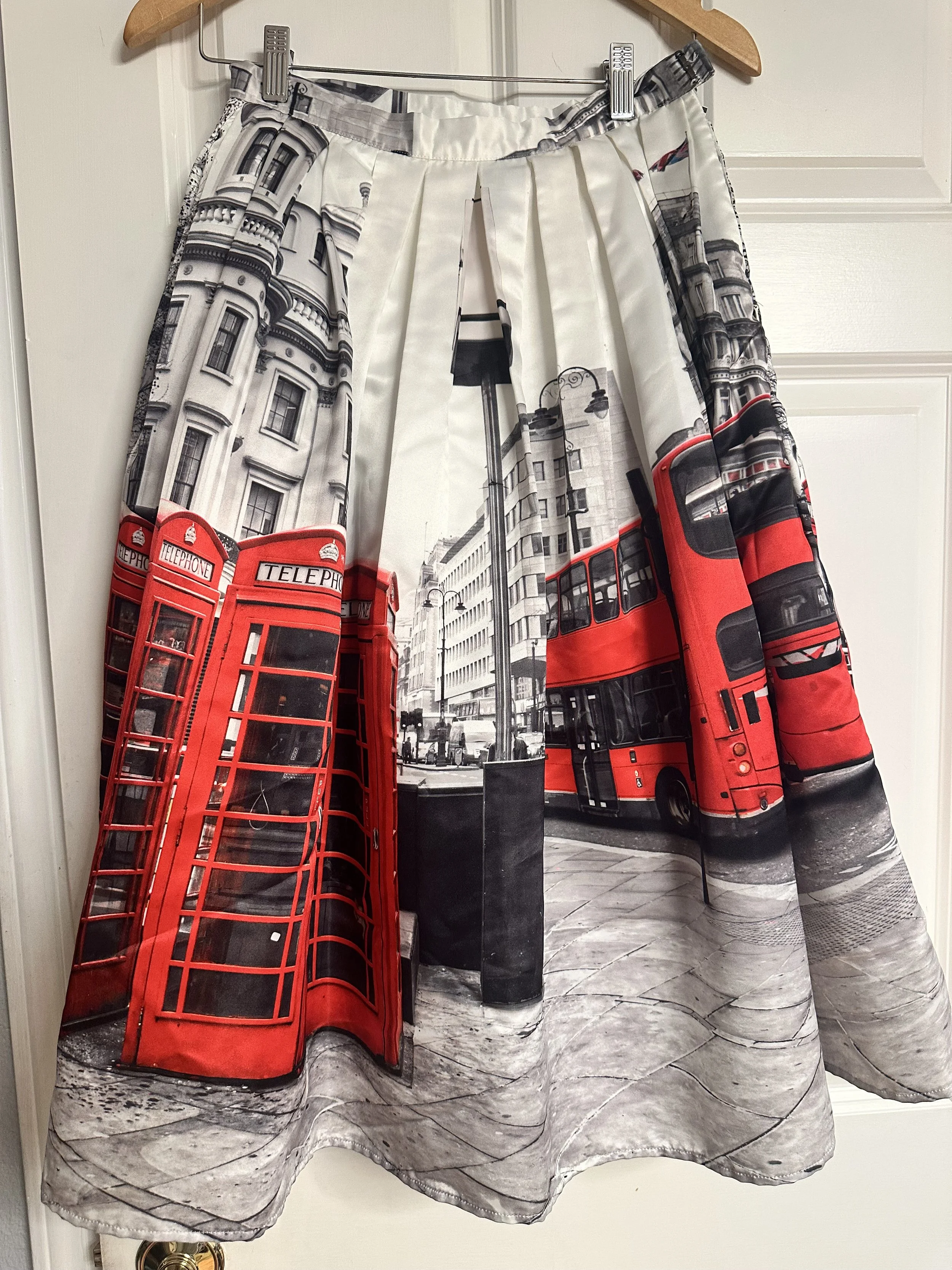 A curtain featuring a black-and-white city street scene with a red telephone booth, black lamp posts, and a double-decker bus.