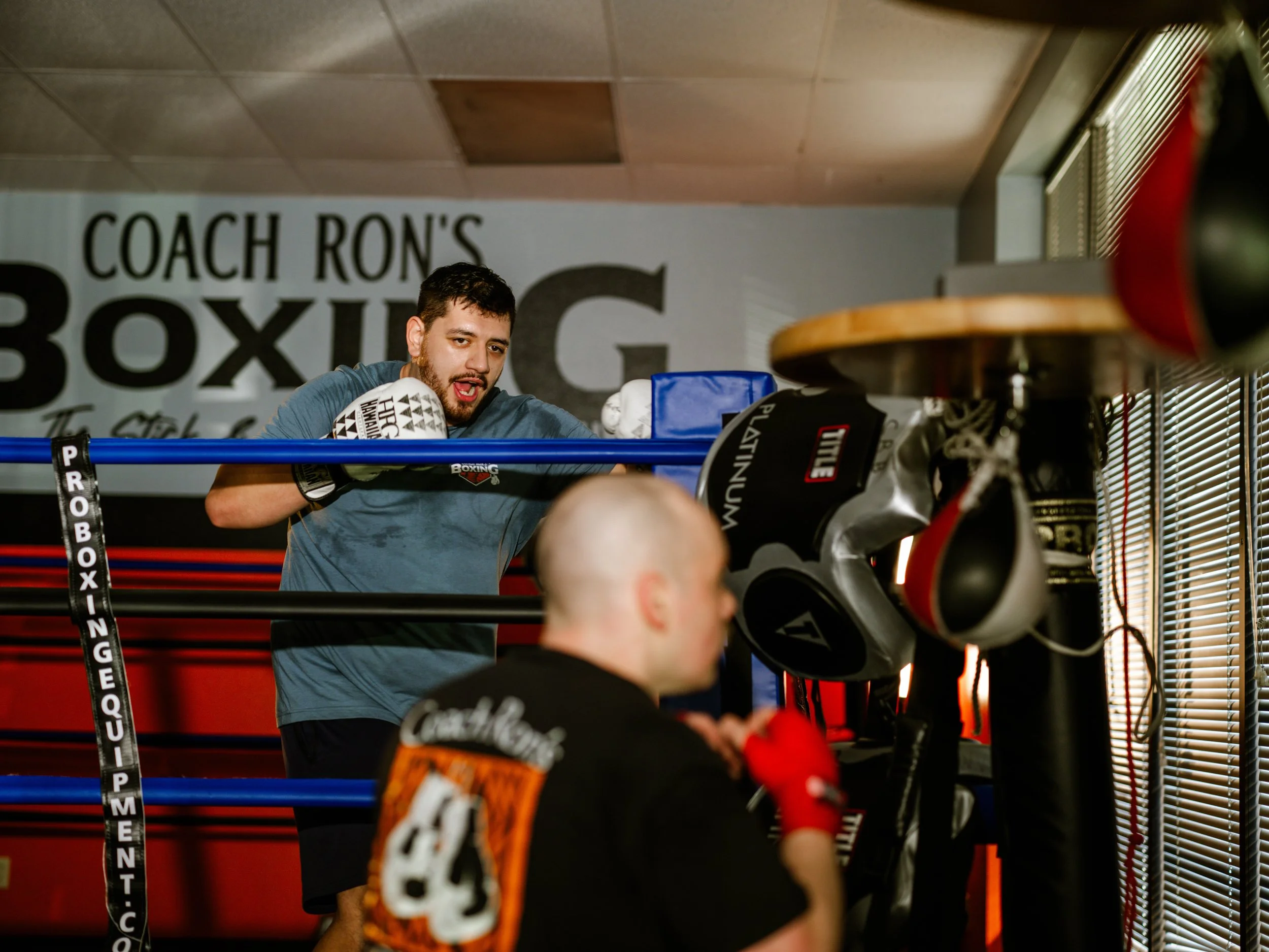 Coach Justin Ah Chan working one-on-one with a boxer in the ring during a training session at Coach Ron's Boxing