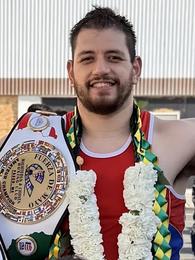 Coach Justin Ah Chan holding a championship belt and wearing flower leis after a win