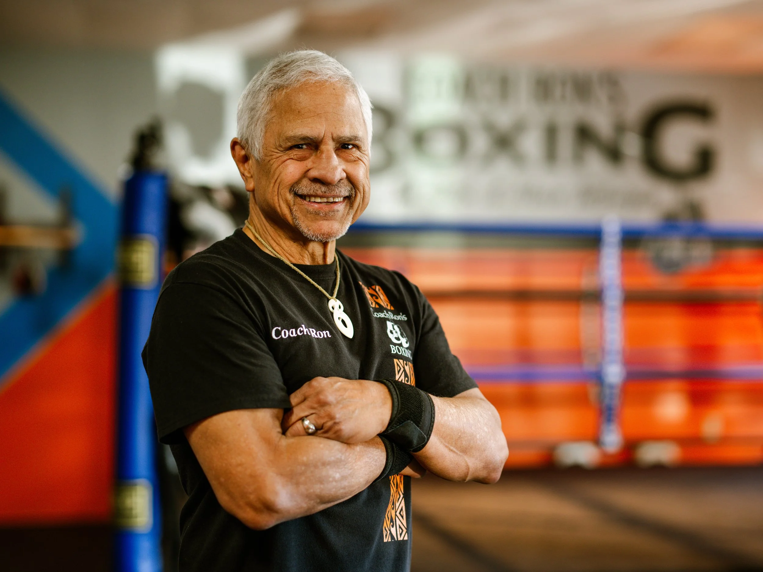 Coach Ron Richardson smiling with his arms crossed beside the ring at his Bremerton gym