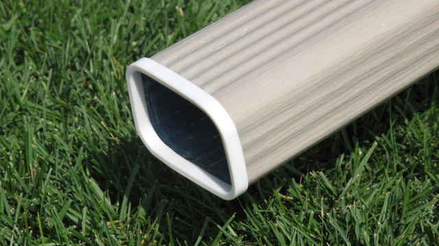 a taupe gutter downspout with a white SpoutTrim cap covering the sharp edges