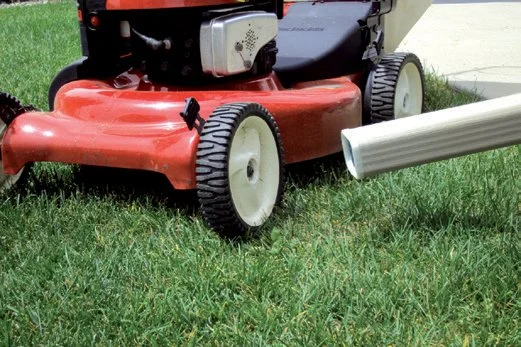 a lawnmower next to a downspout protected with a SpoutTrim cap