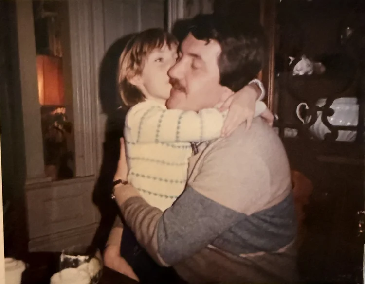 A young child embracing her father in a vintage photo