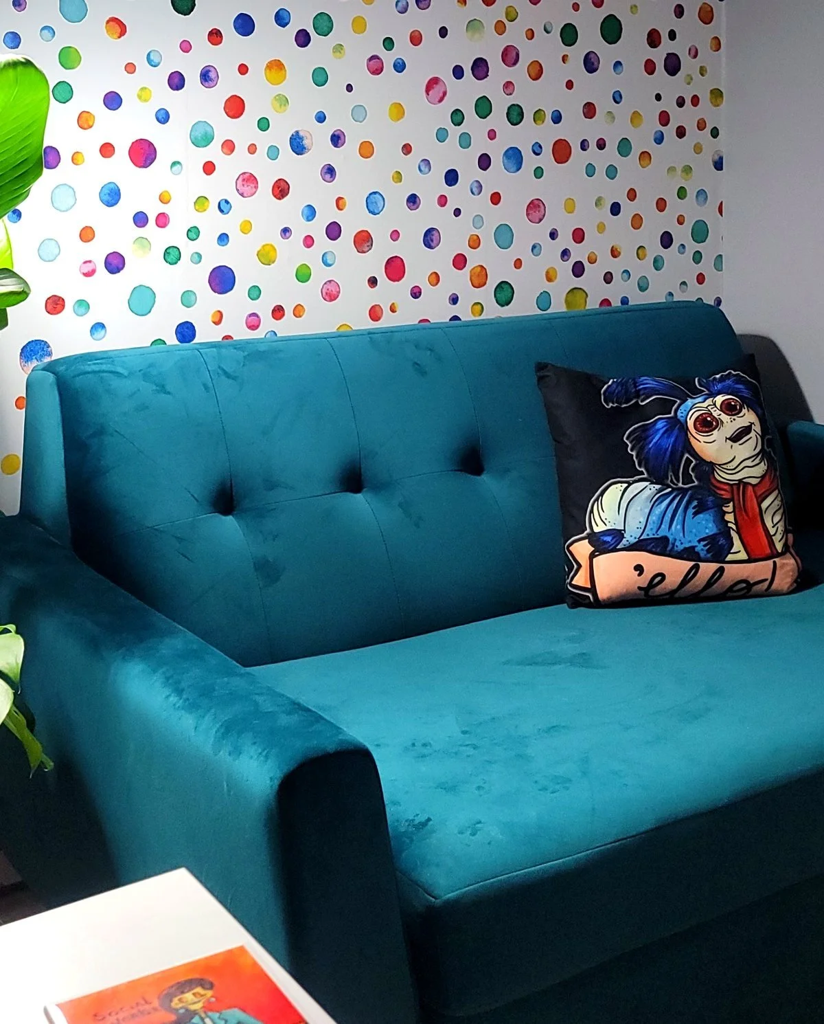 Cozy online therapy setup at Ala Therapy Collective in Oklahoma, a teal velvet couch against a colorful watercolor dot wall