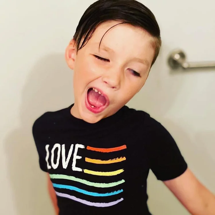 Young child laughing in a black T-shirt with a rainbow LOVE design
