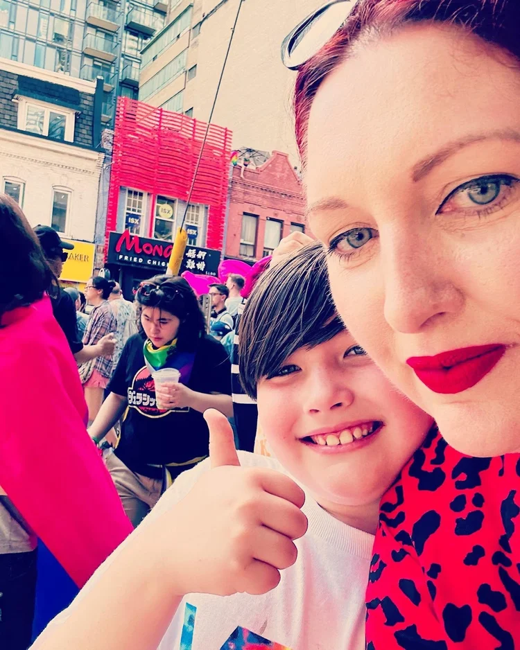 Parent and child taking a selfie together at a Pride street festival