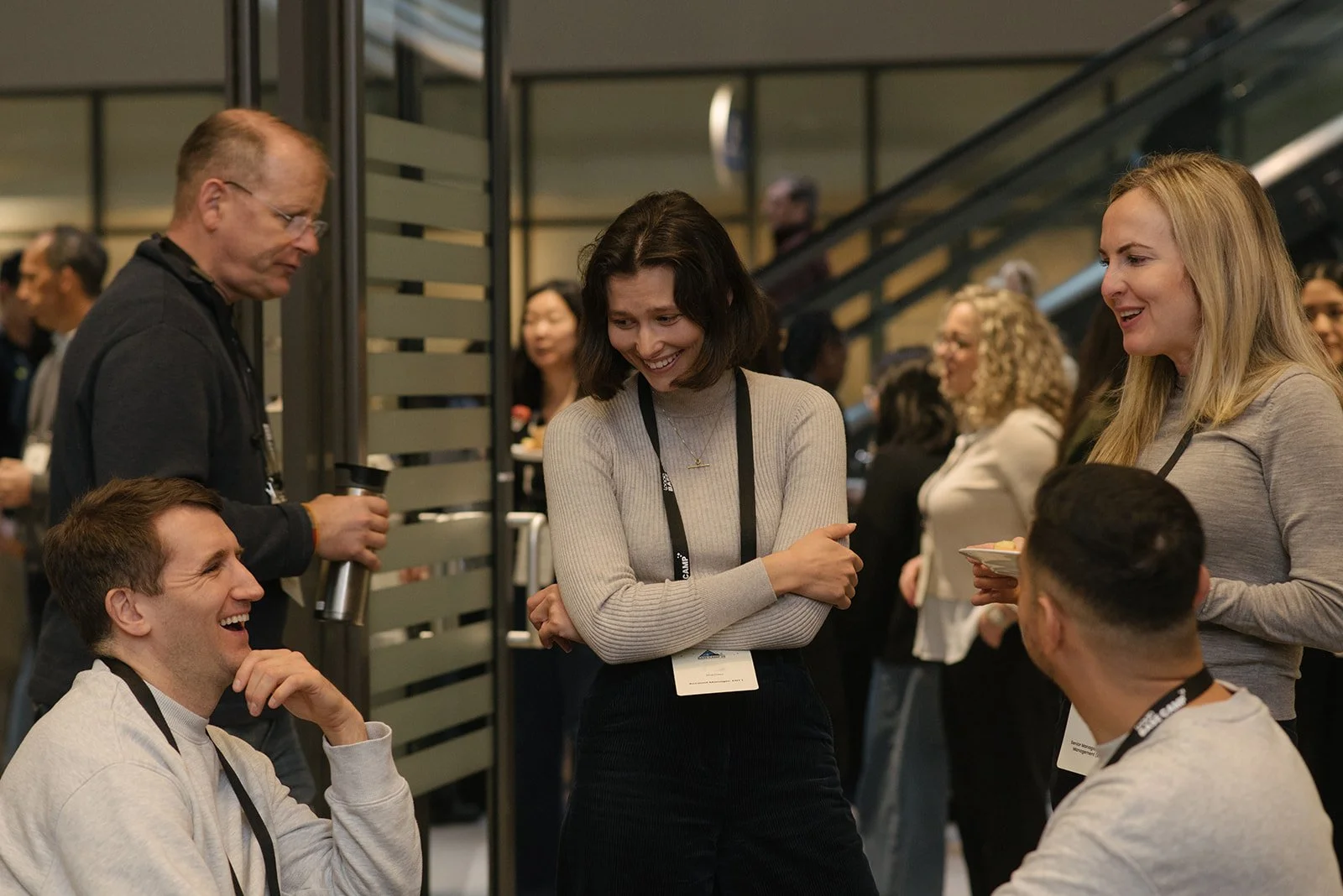 Group of young adults engaging in a lively conversation at a conference in Toronto at the MaRS Discovery District with some smiling and laughing.