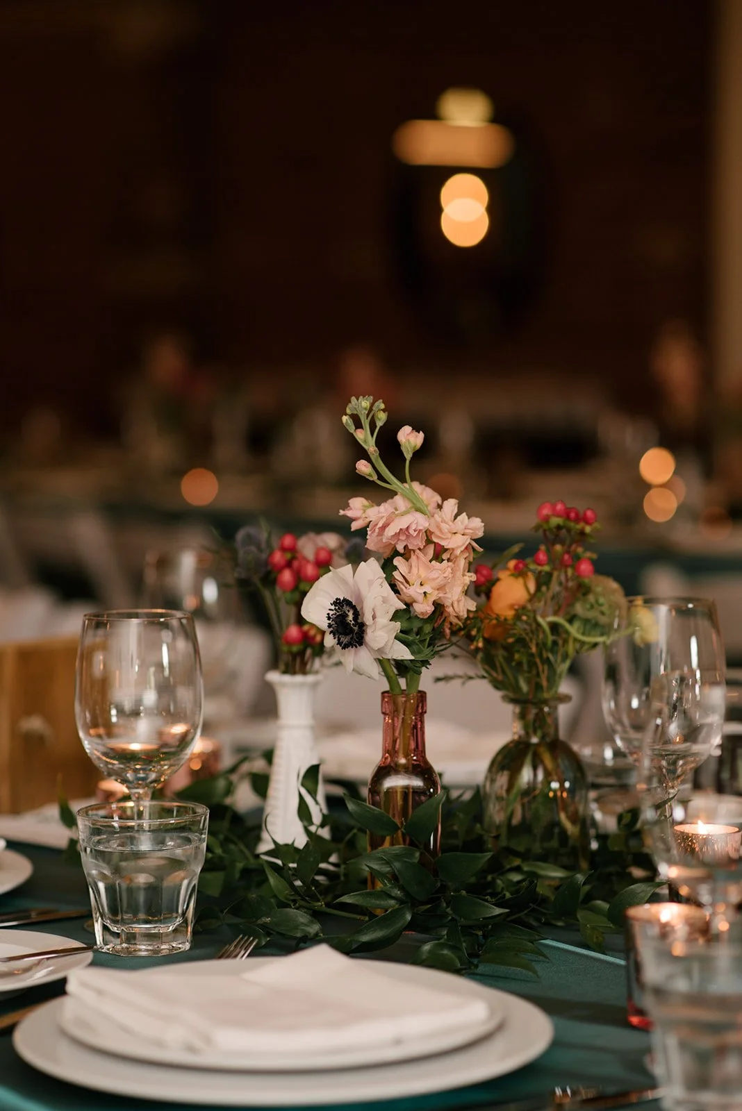 An elegant table centerpiece with pink and white flowers in glass vases, surrounded by wine glasses, water glasses, plates, and silverware, set for a wedding reception at The Broadview Hotel.