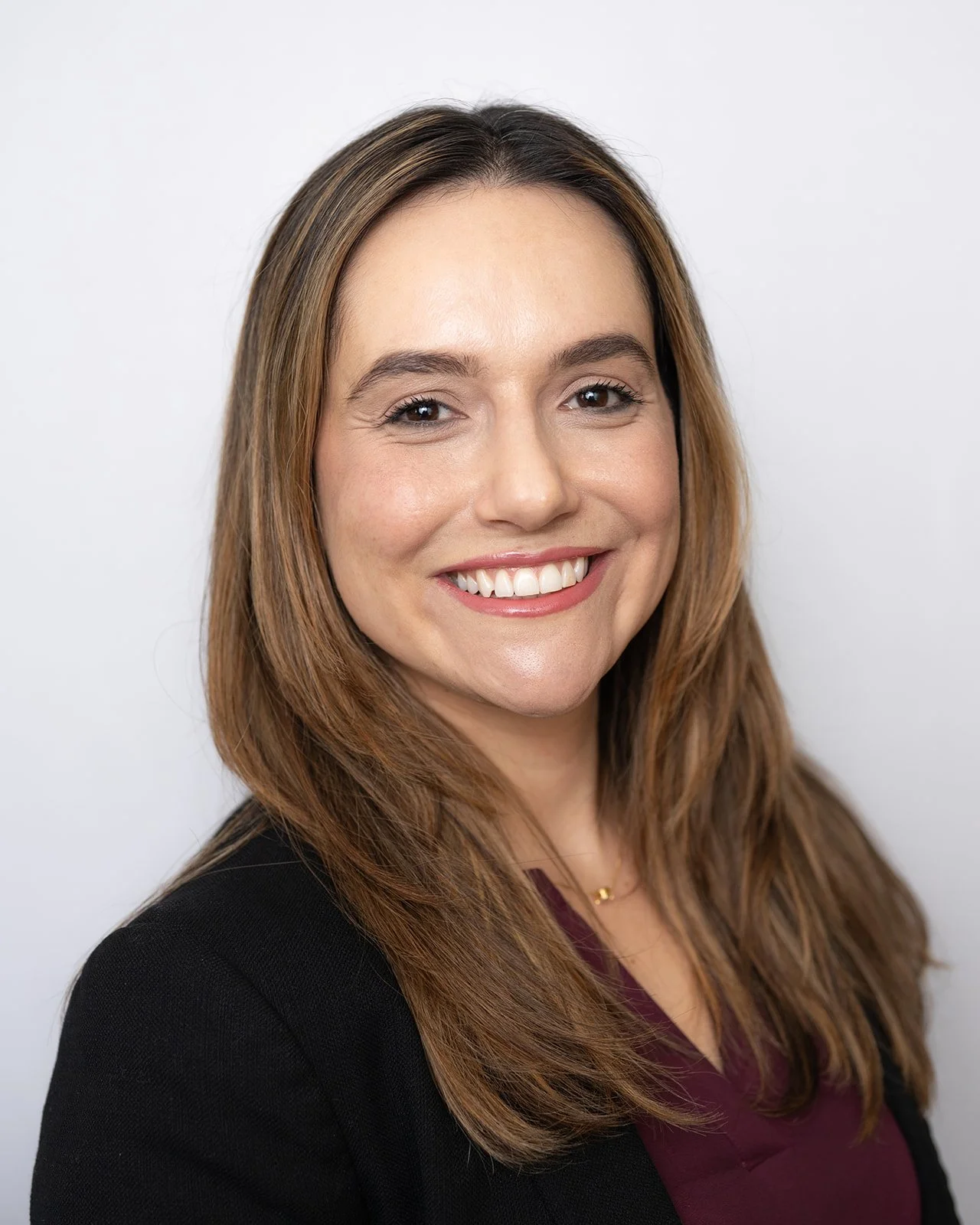 A woman with shoulder-length light brown hair smiling at the camera against a plain white background.