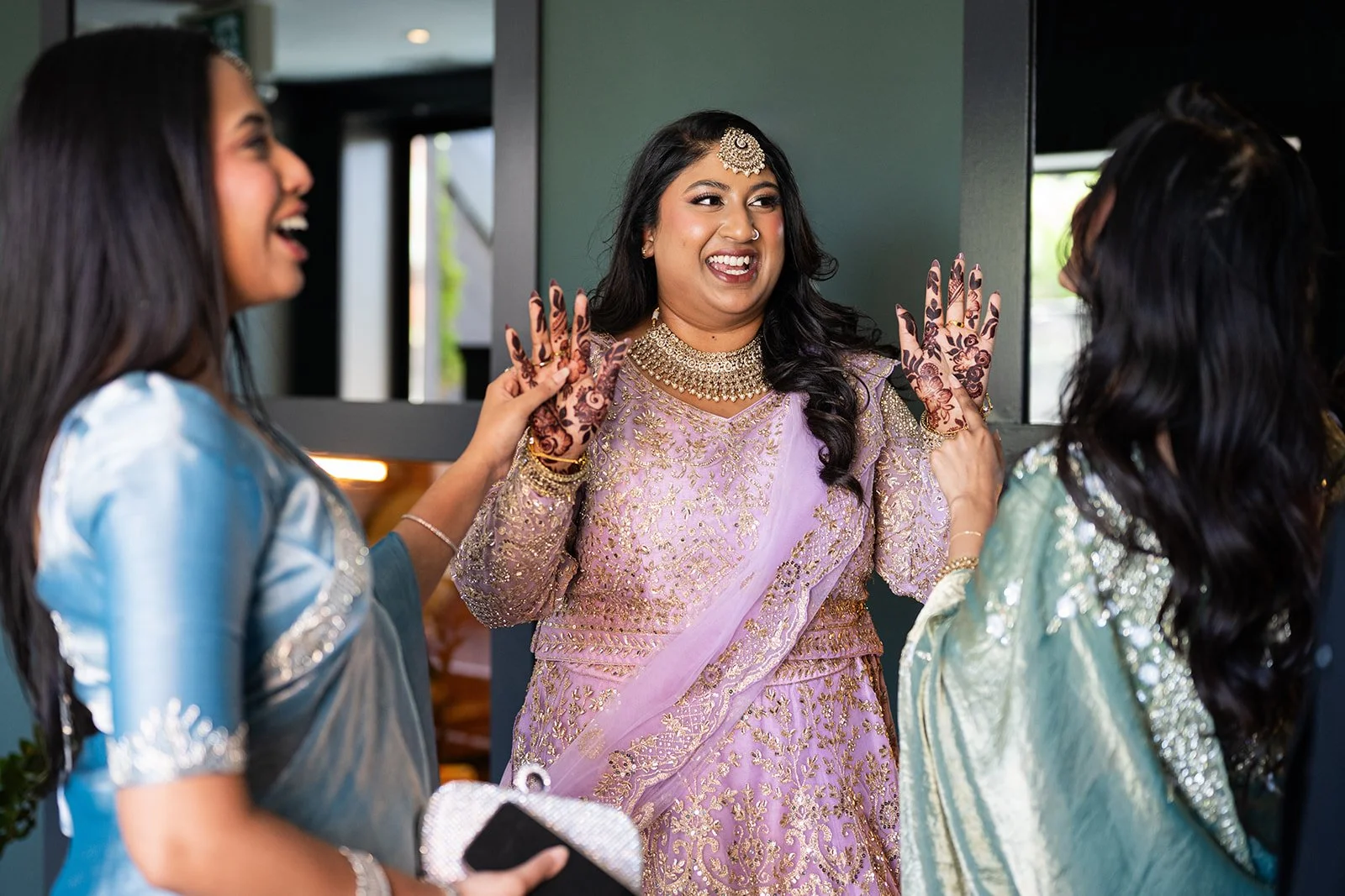 Women in traditional Indian attire smiling and greeting each other before a wedding ceremony is about to begin at The Broadview Hotel in Toronto.