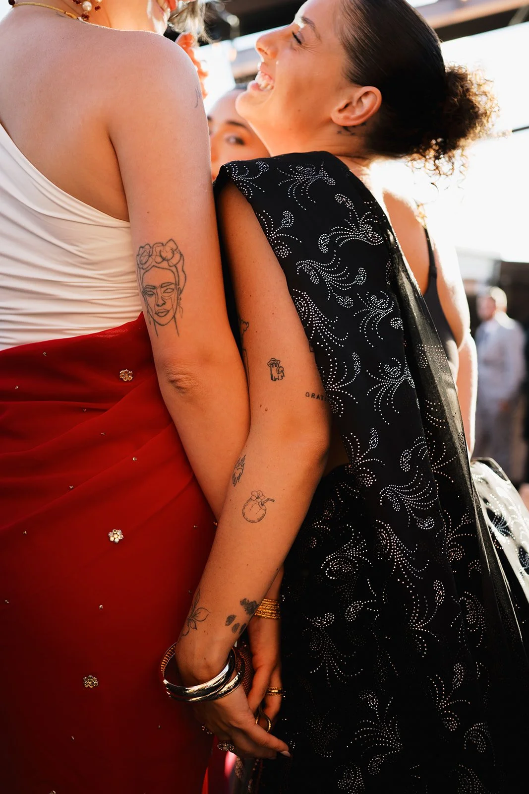 Two women embracing, showing their tattoos on their arms, after a wedding ceremony at the Broadview Hotel in Toronto.