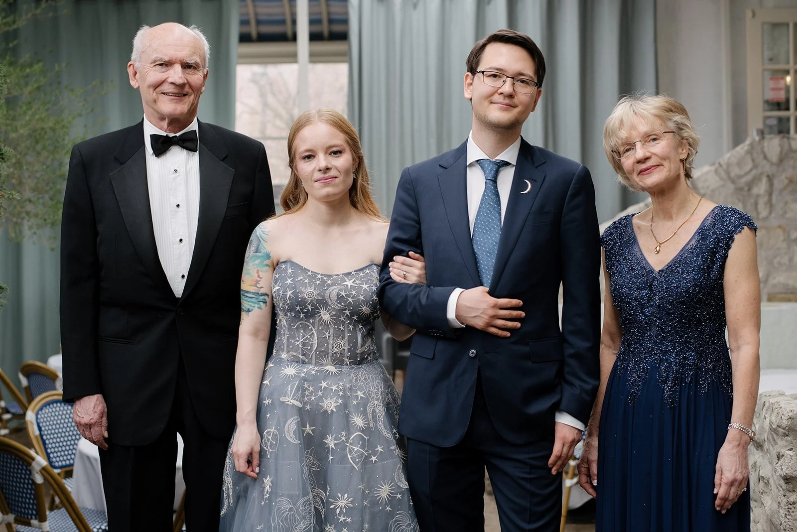 A family dressed in formal attire, standing on the indoor terrace at Auberge du Pommier in Toronto.