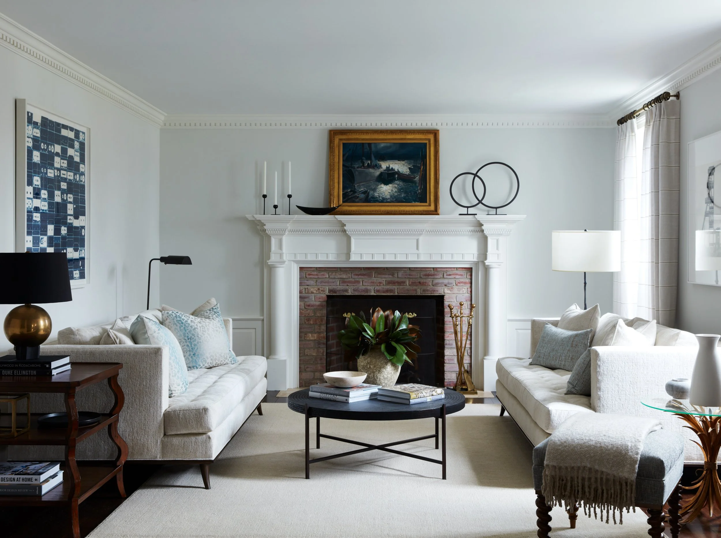 Neutral living room with ivory sofas, subtle leopard print pillows, layered coffee table styling, and classic fireplace, designed by Barrett Oswald Designs in Westchester, NY