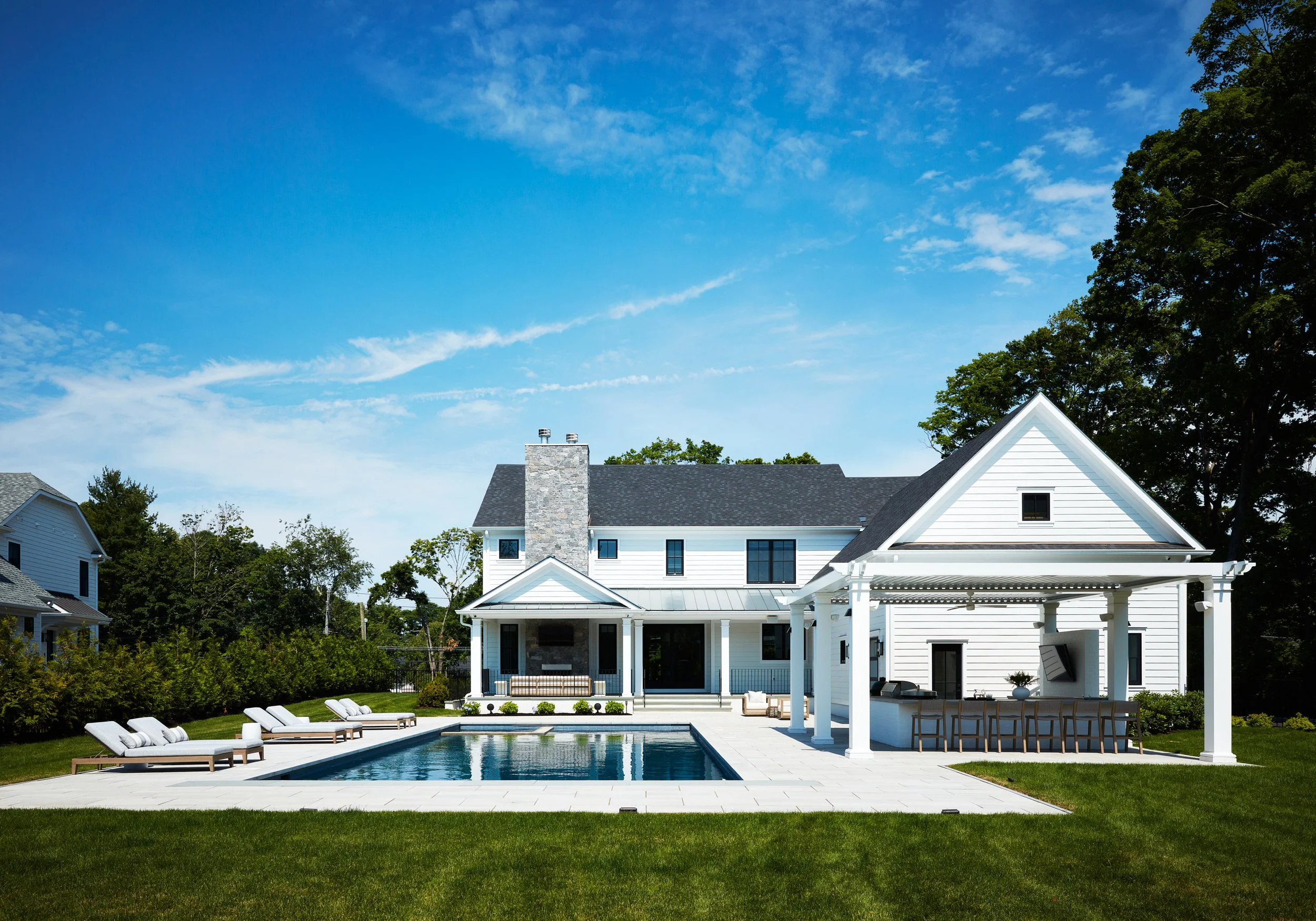 Renovated Harrison home exterior with a swimming pool, covered outdoor kitchen pavilion, and white clapboard architecture.